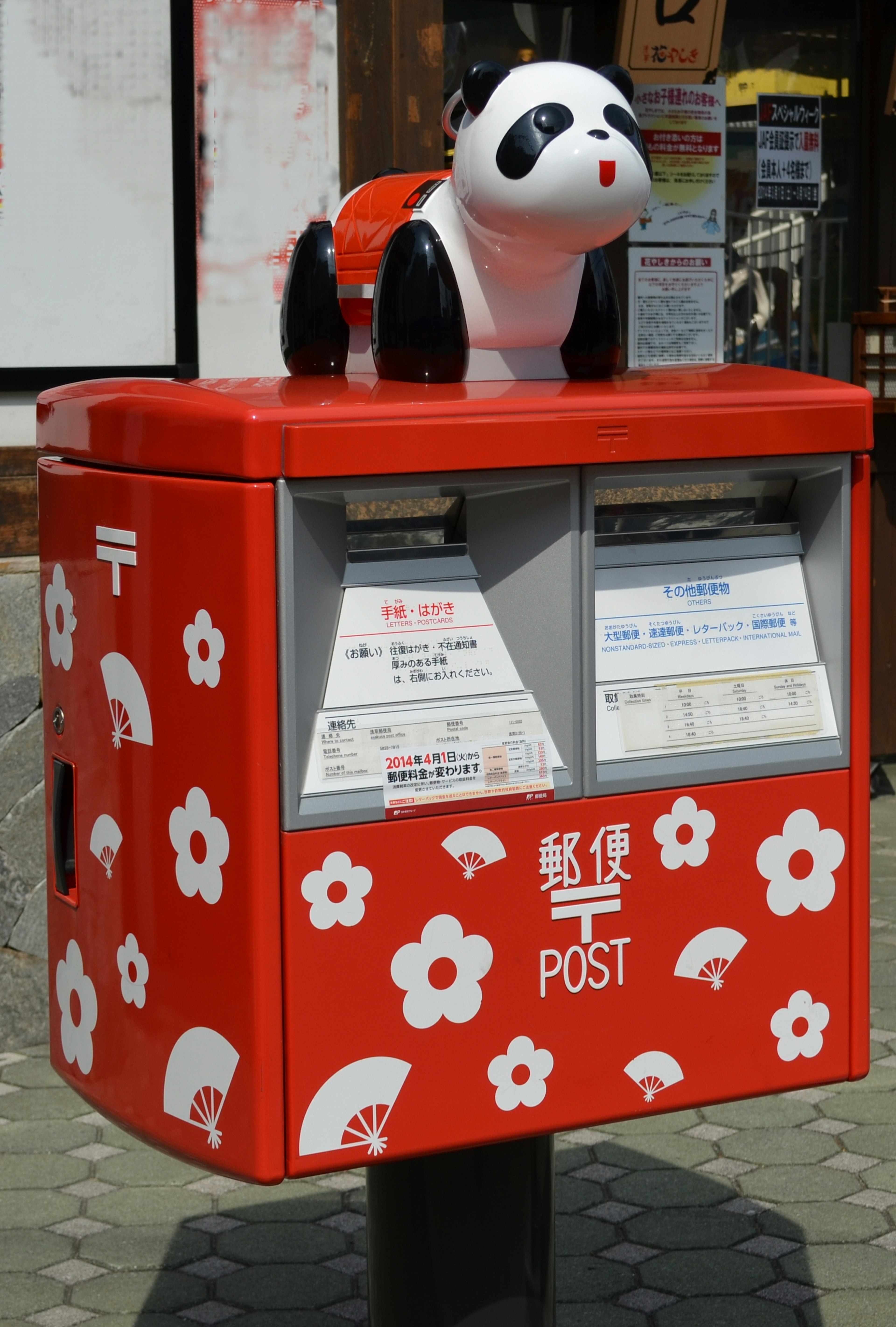 Red mail post box with a panda figurine on top featuring floral design