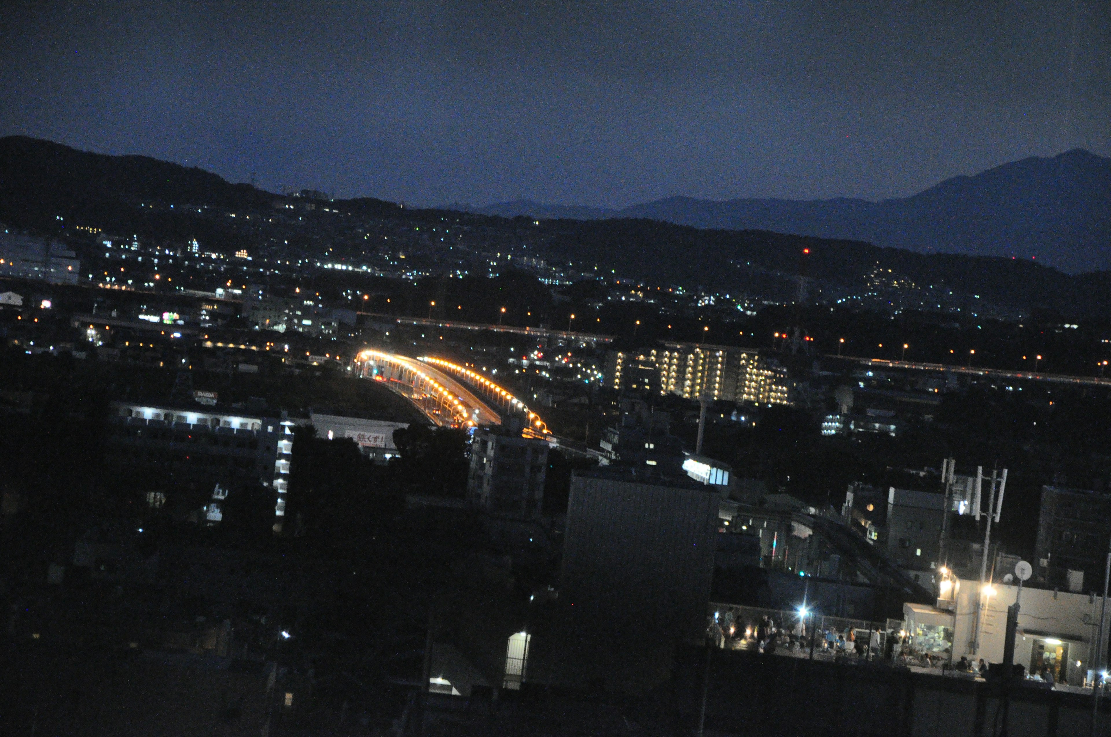 Night cityscape with glowing light trails and mountains