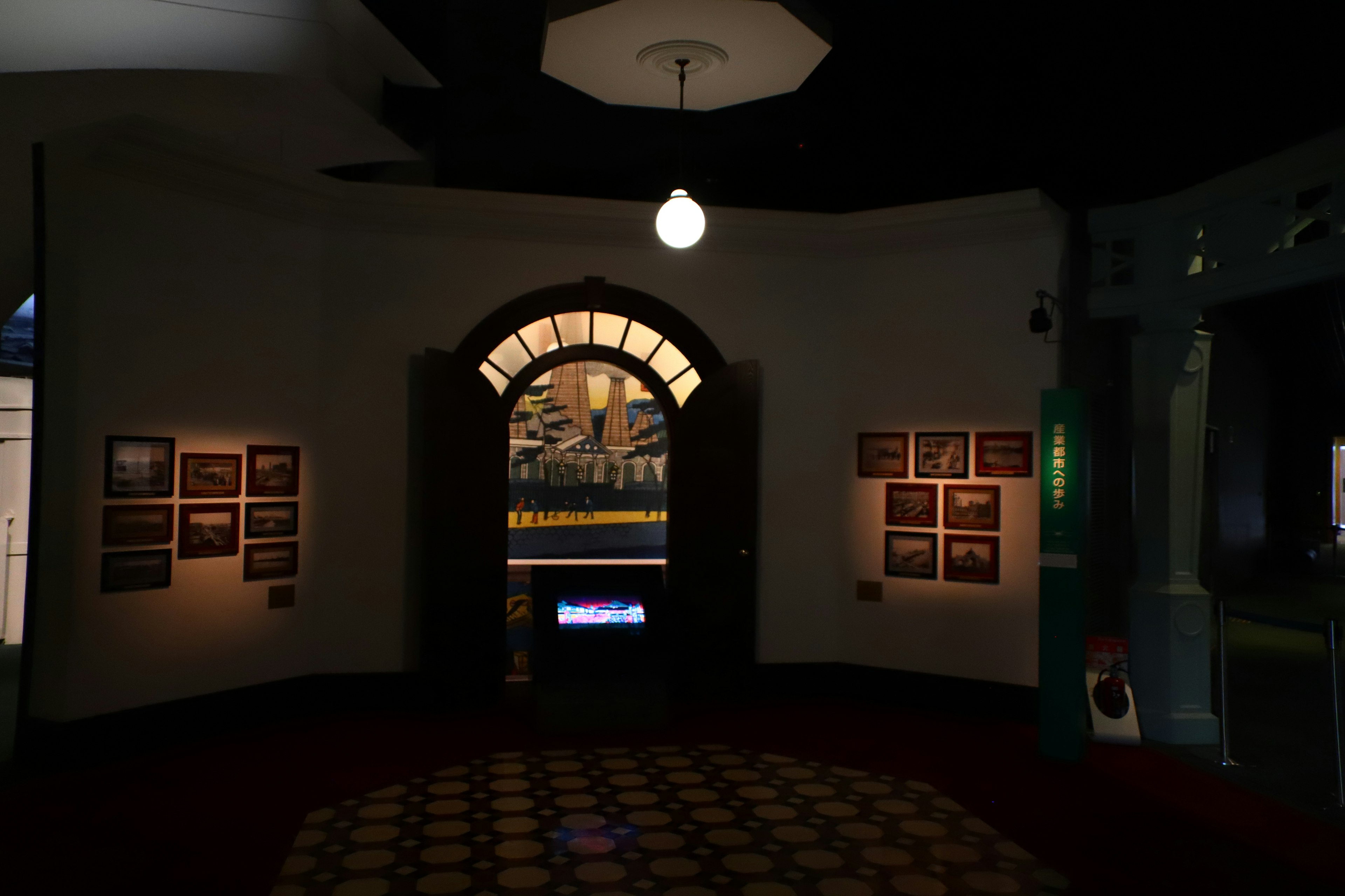 Salle avec une entrée en arc et des murs affichant des photographies