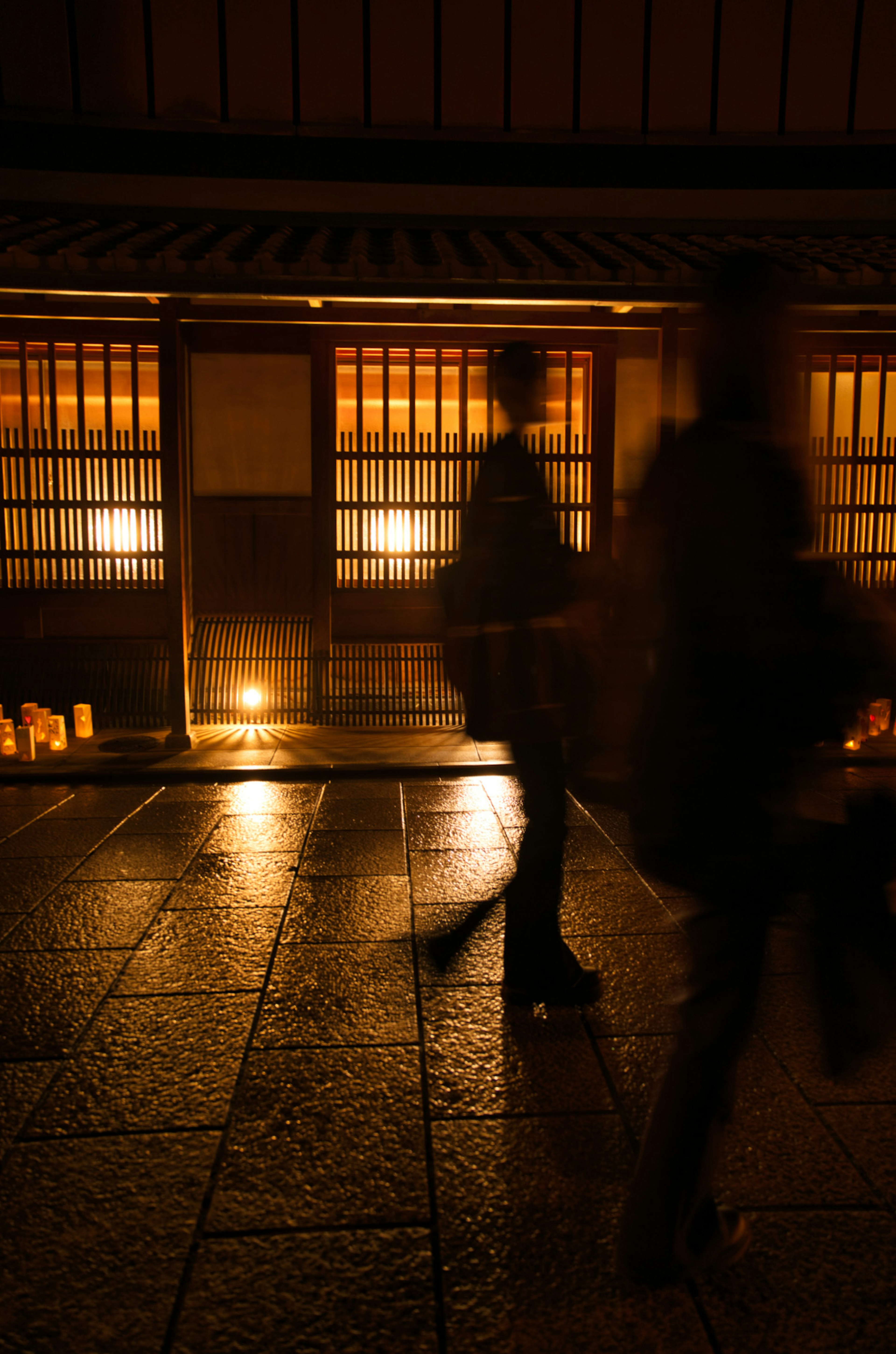 Persone che camminano per strada di notte con luce calda dalle finestre