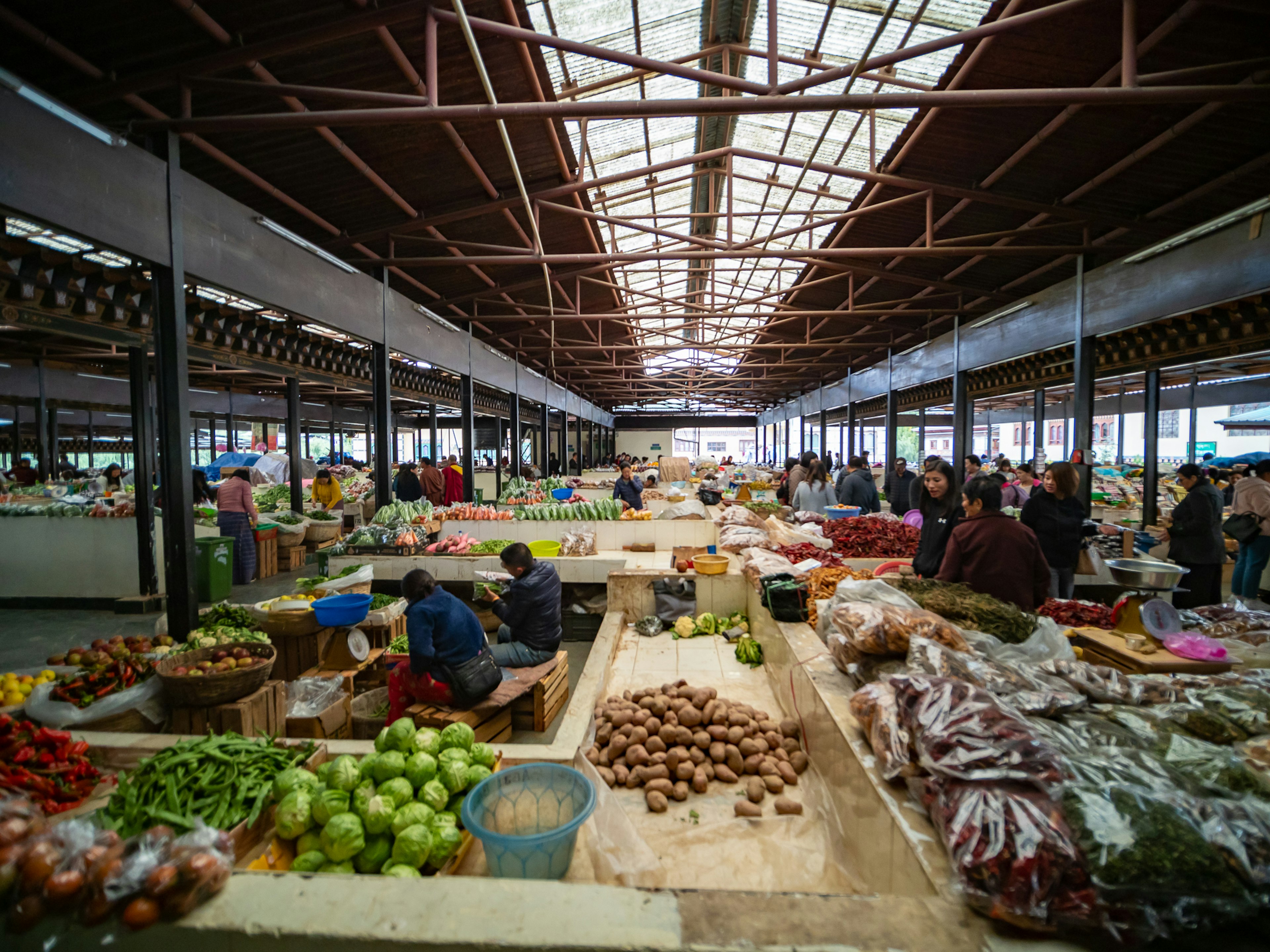 Pemandangan interior pasar yang dipenuhi dengan buah-buahan dan sayuran berwarna-warni