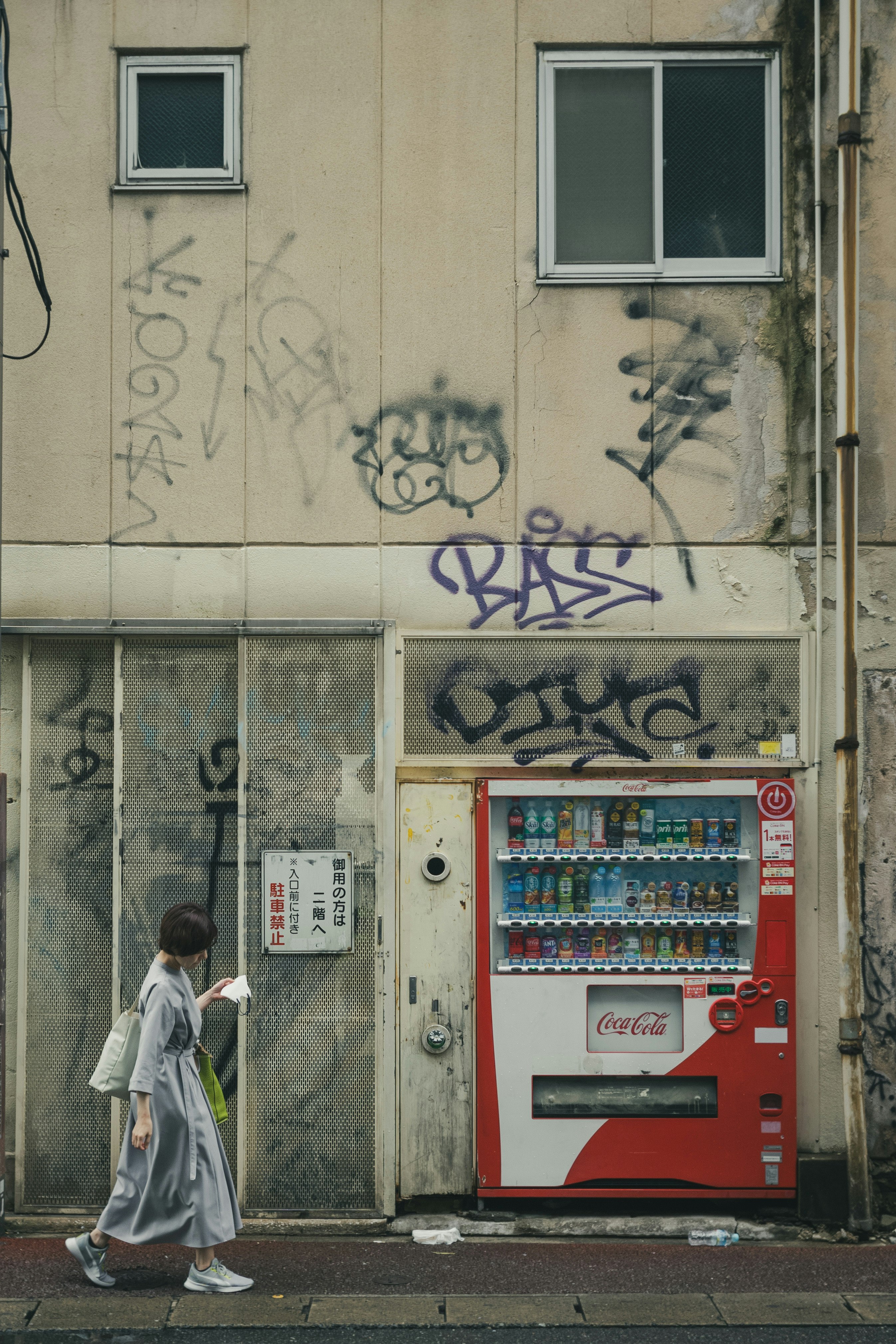 Una donna che cammina davanti a un muro coperto di graffiti con una macchina automatica