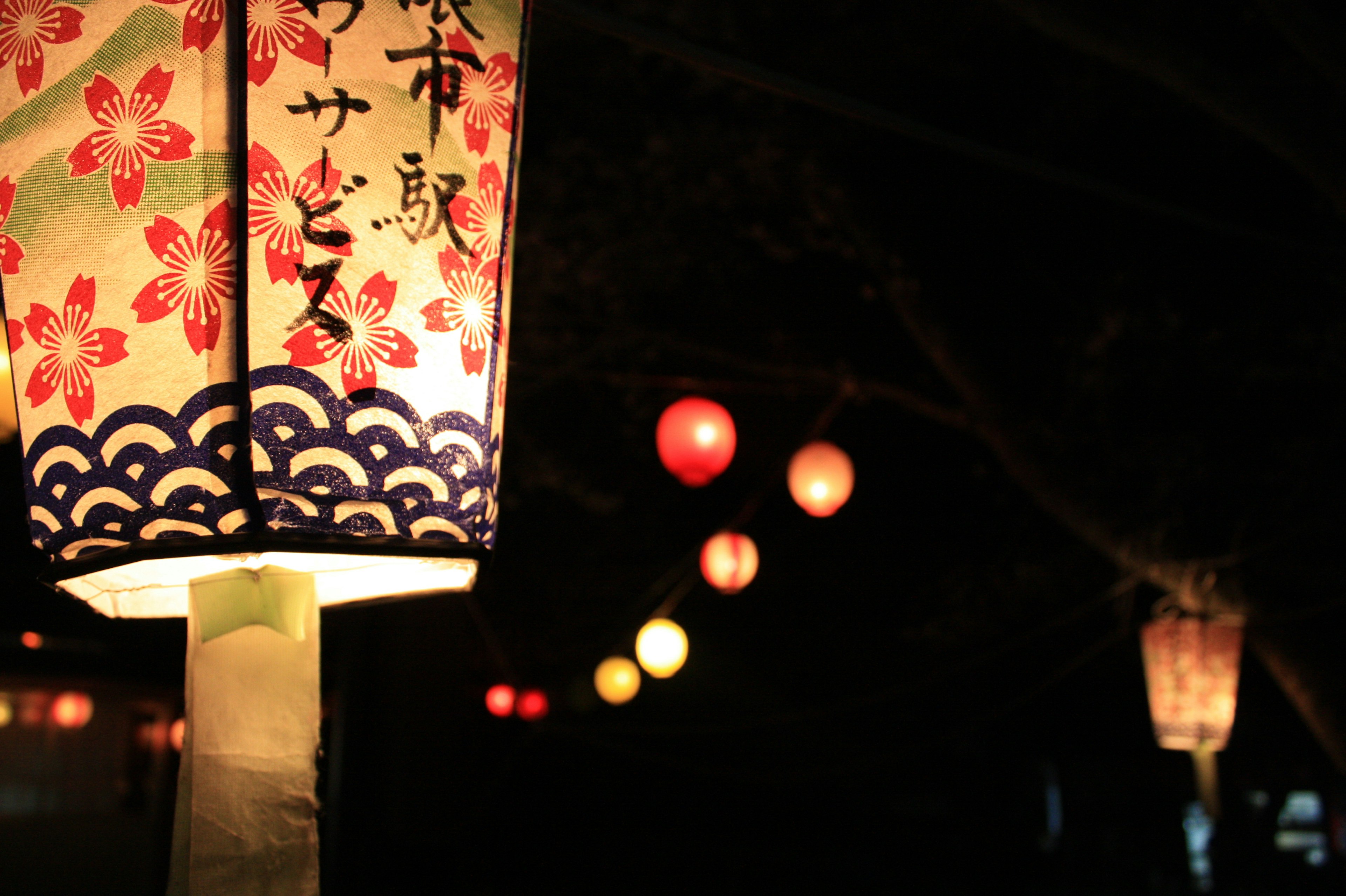 Lampions colorés et lampe à motif de fleurs de cerisier dans une scène nocturne