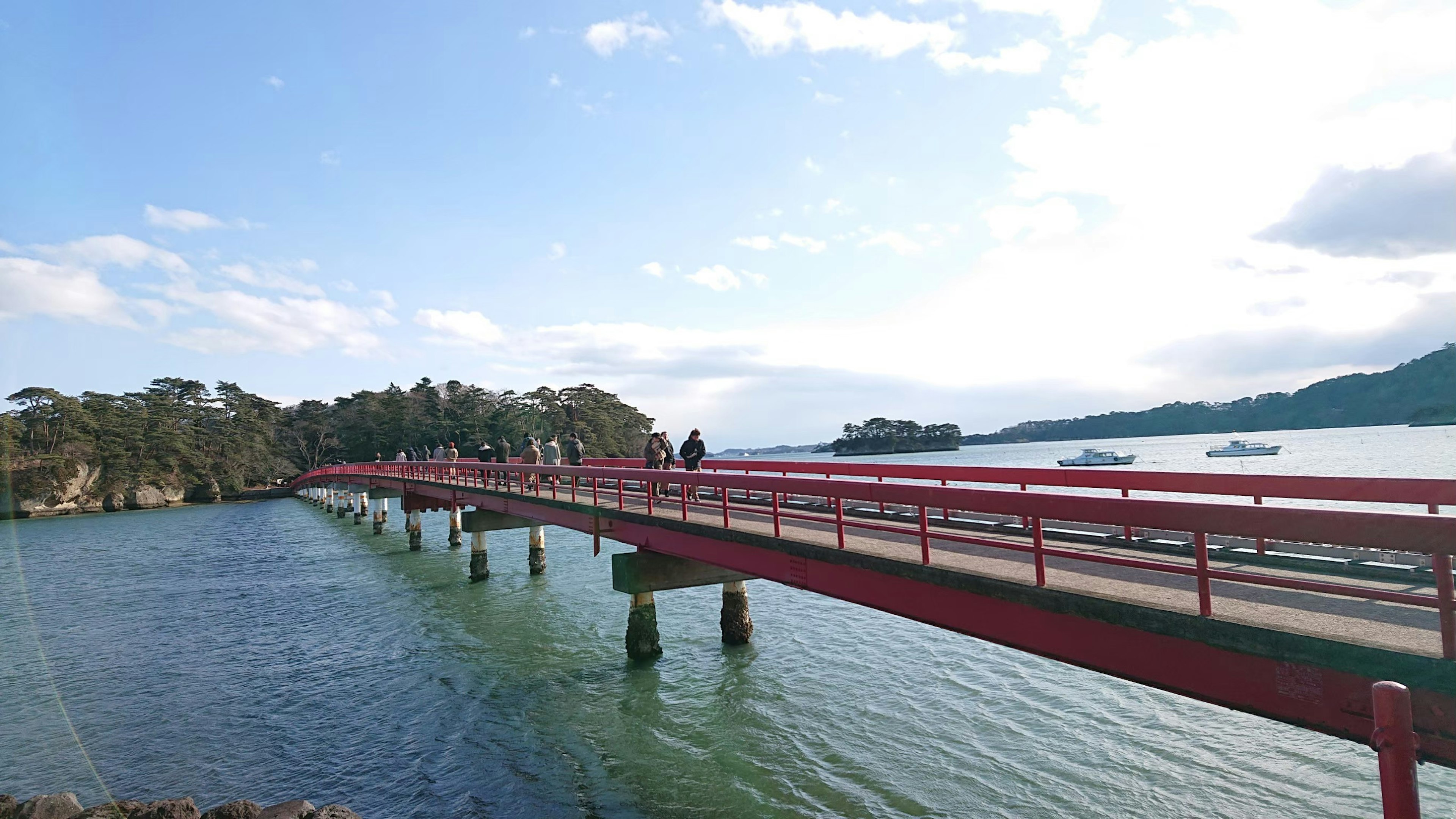 赤い橋が水面を横切り周囲の自然と調和する風景