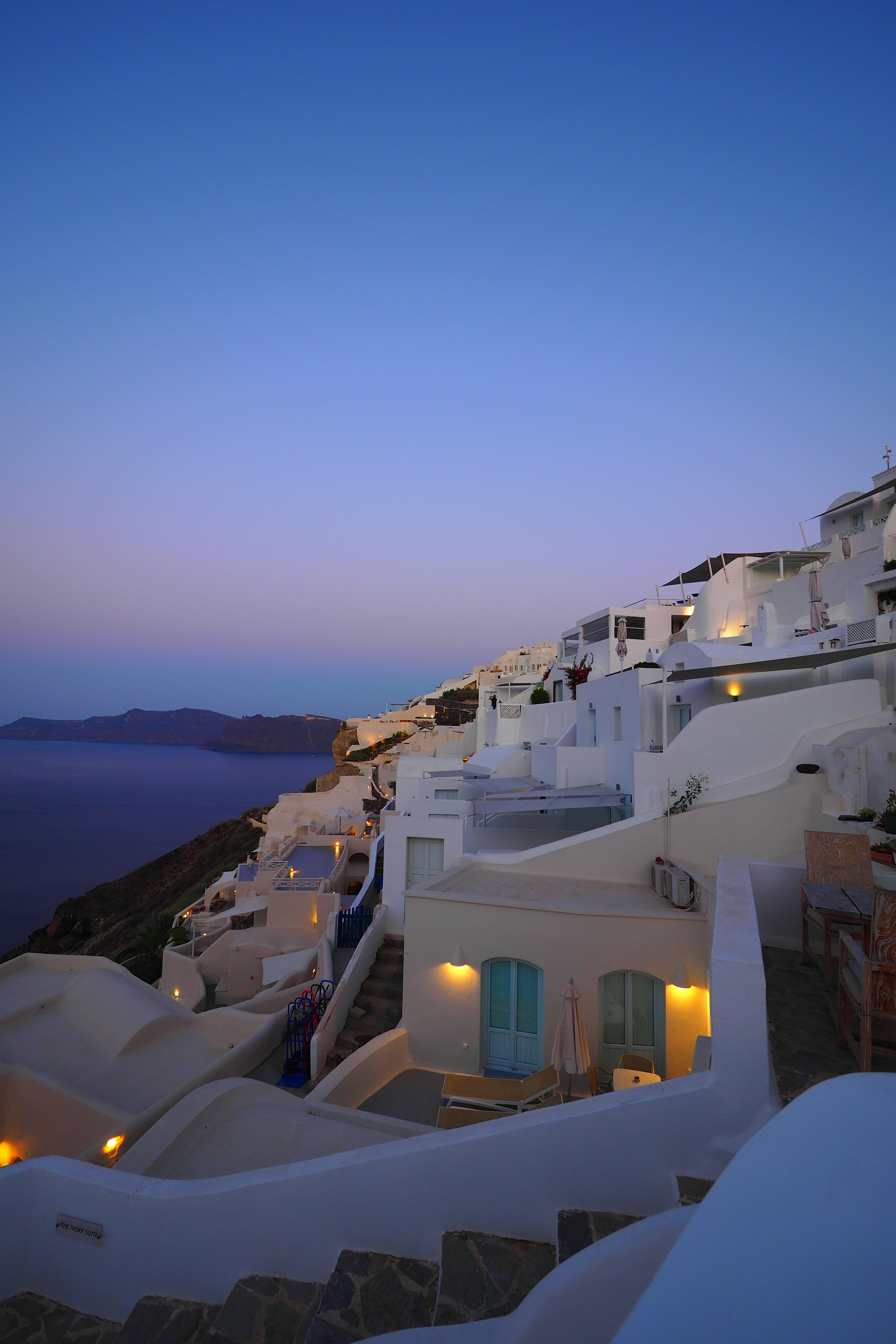 Weiße Gebäude mit blauen Fenstern, beleuchtet von einem schönen Sonnenuntergang in Santorin