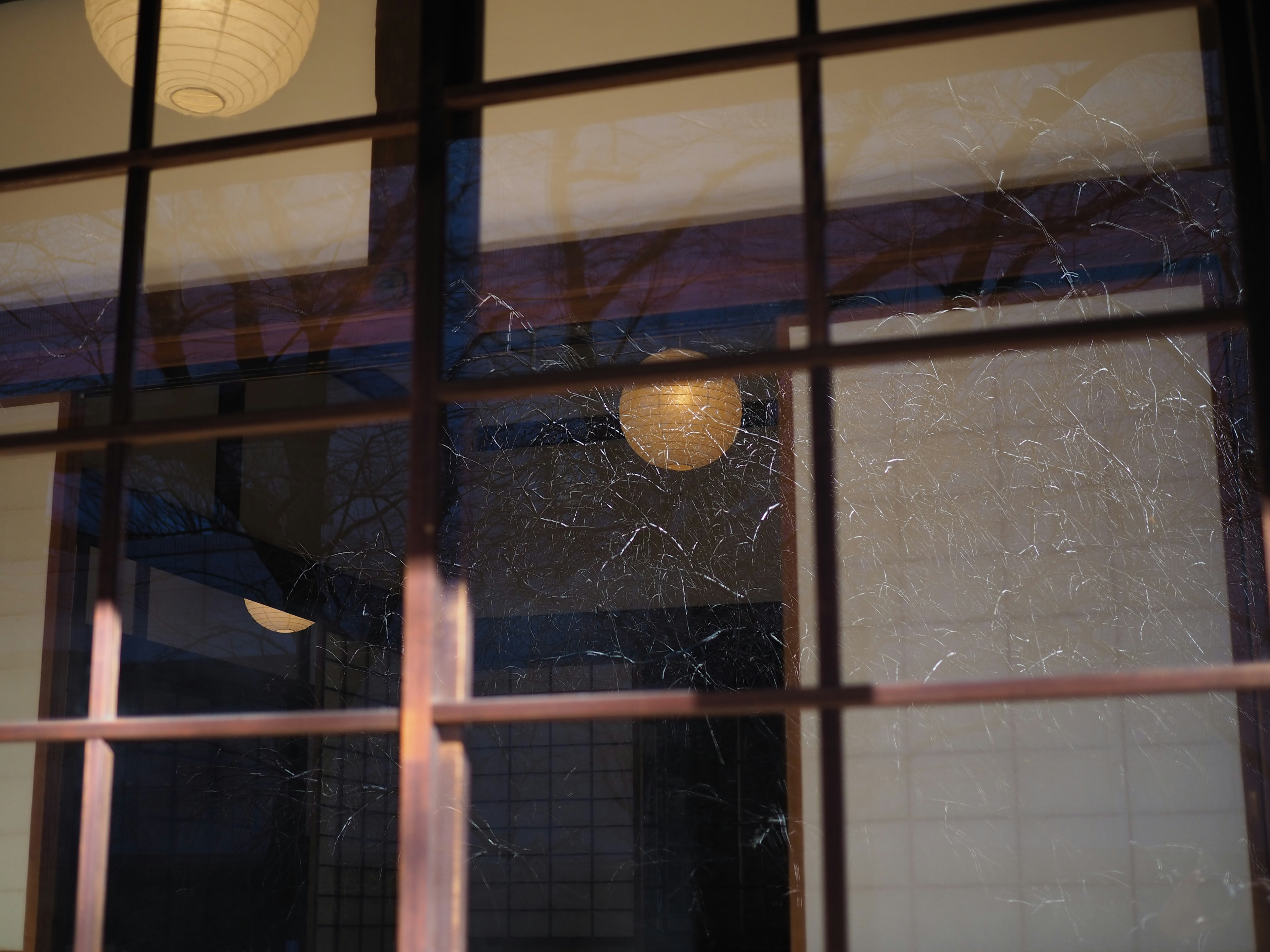 Exterior view of a wooden window frame in a traditional Japanese room showcasing translucent shoji screens and decorative lanterns