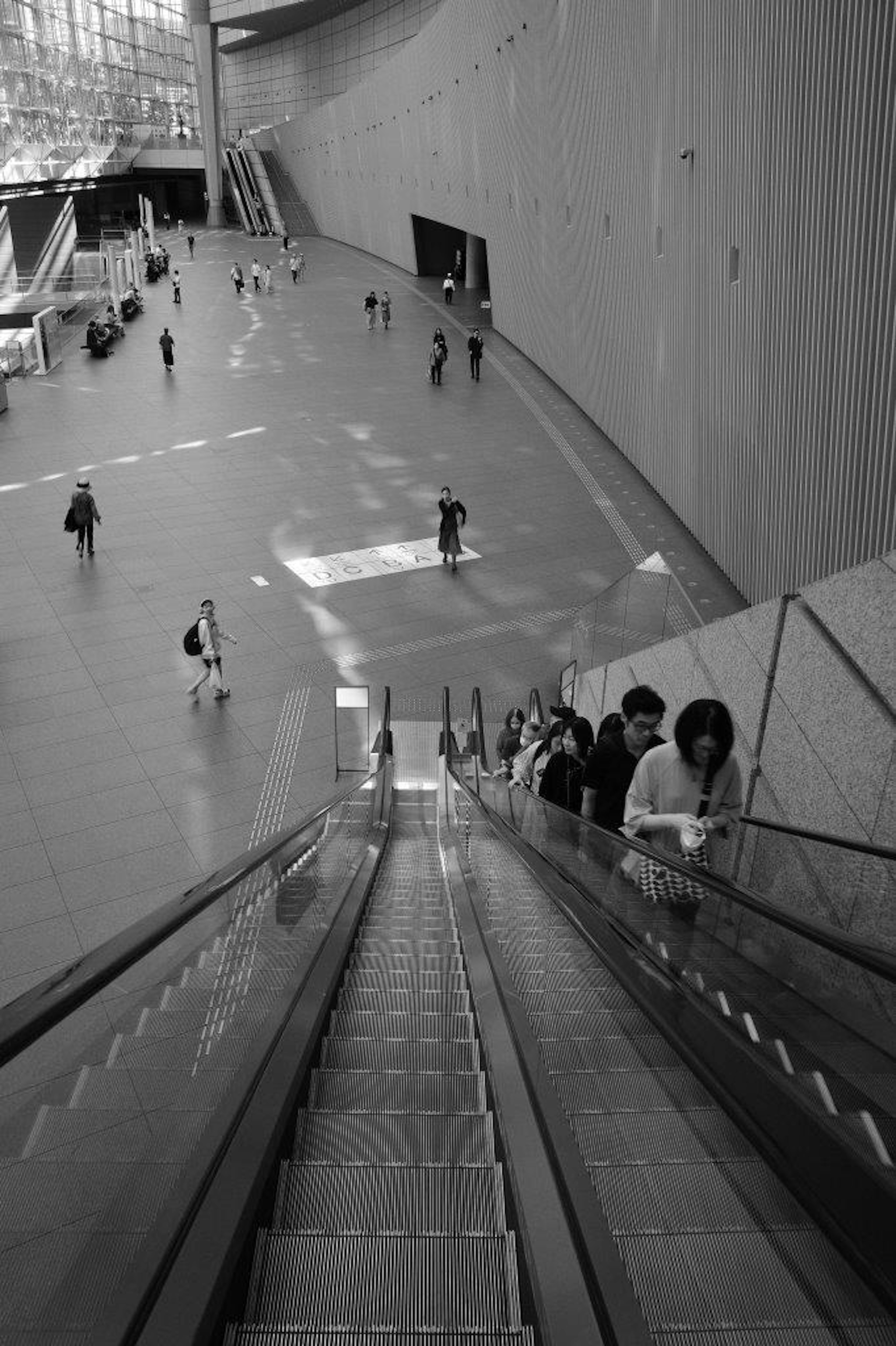 Blick von einer Rolltreppe in einem modernen Gebäude mit Menschen, die sich unten bewegen