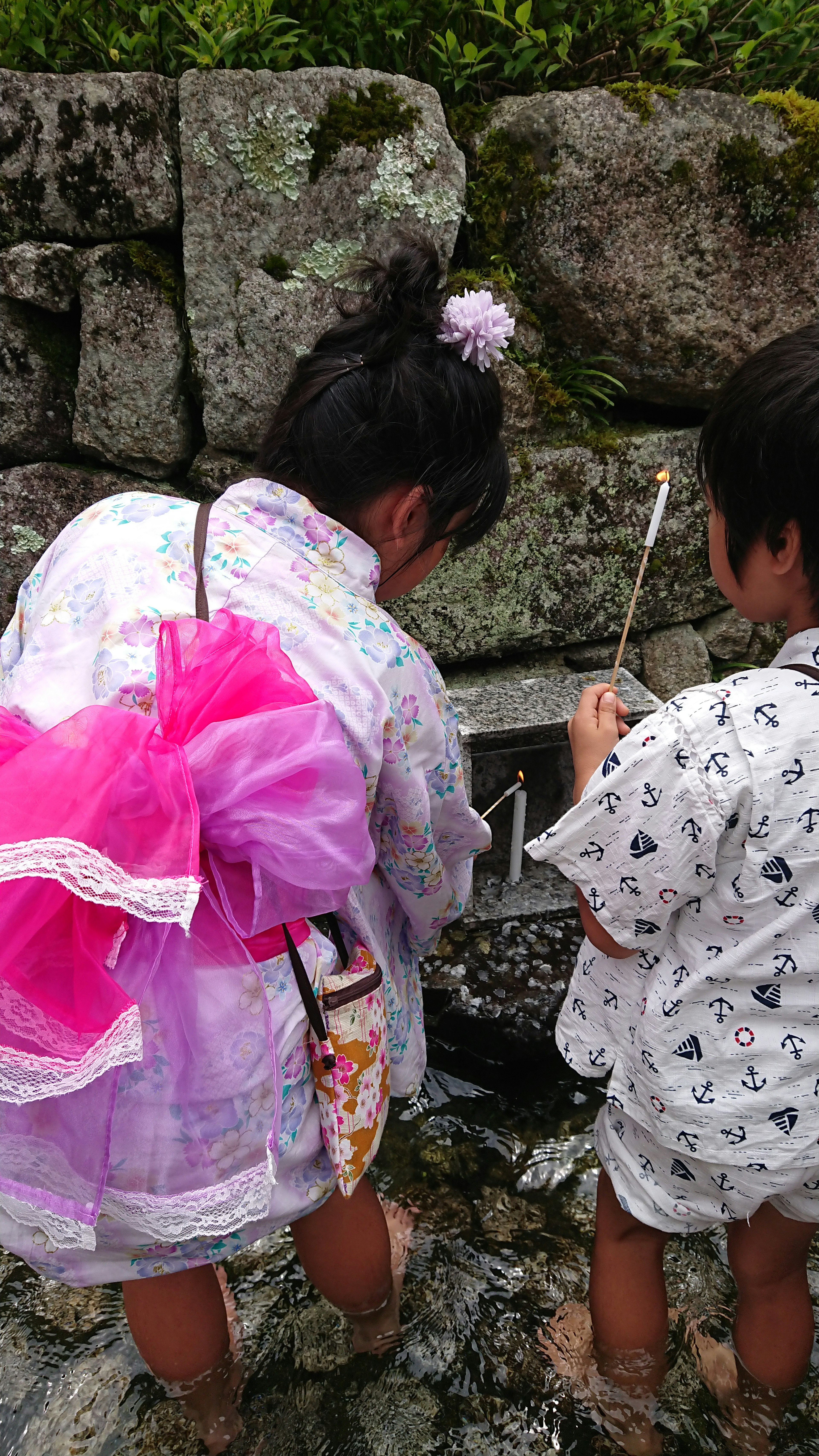 Niños con ropa tradicional sacando agua de un estanque de piedra