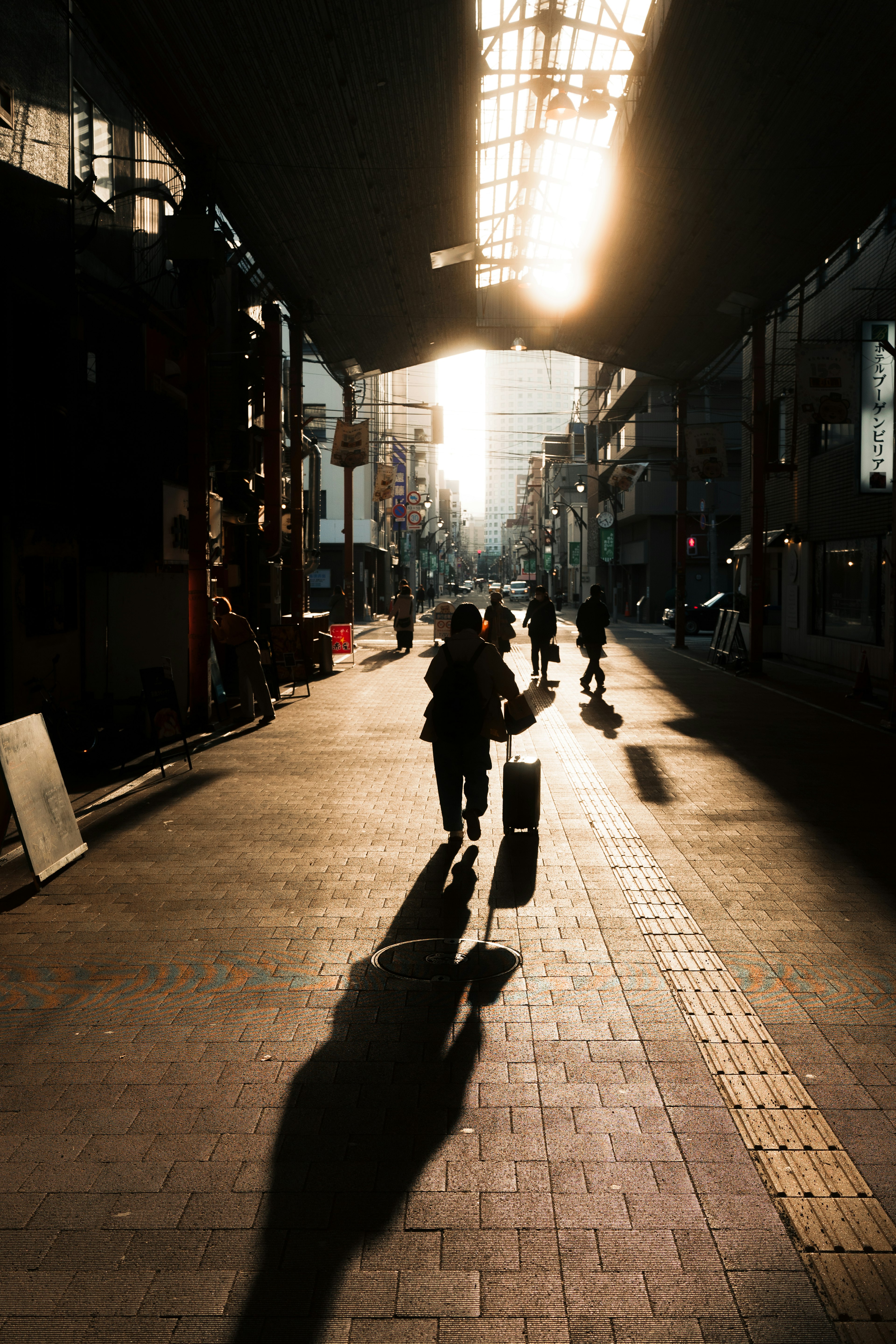 Straßenszene, die vom Sonnenuntergang beleuchtet wird, mit Silhouetten von Menschen