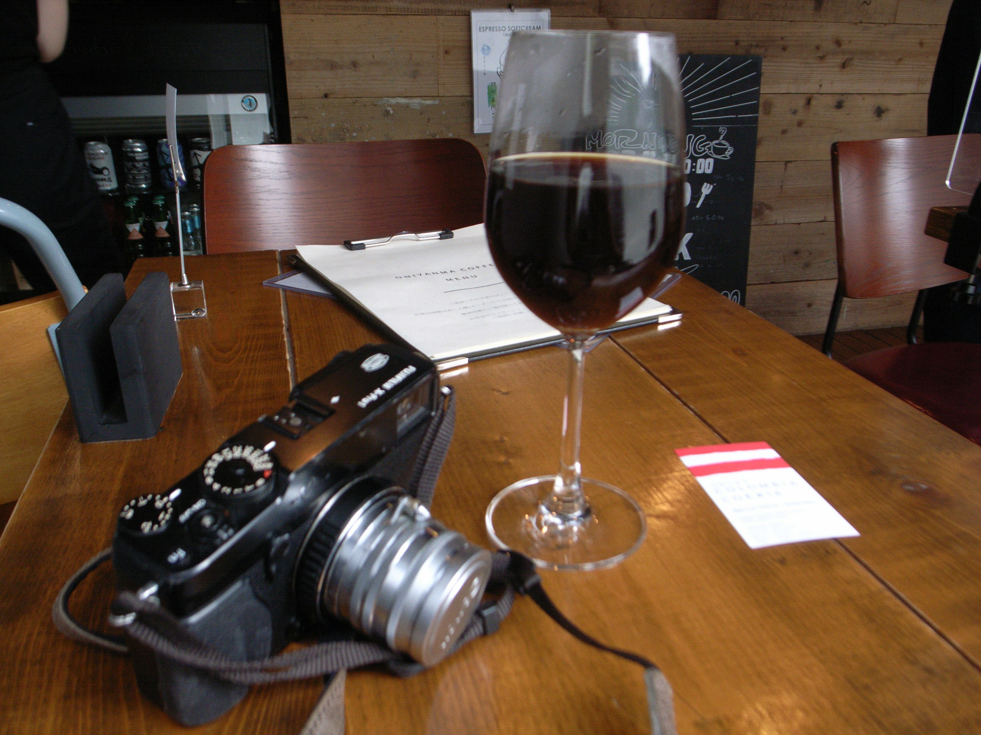 Kamera und Glas Rotwein auf einem Holztisch