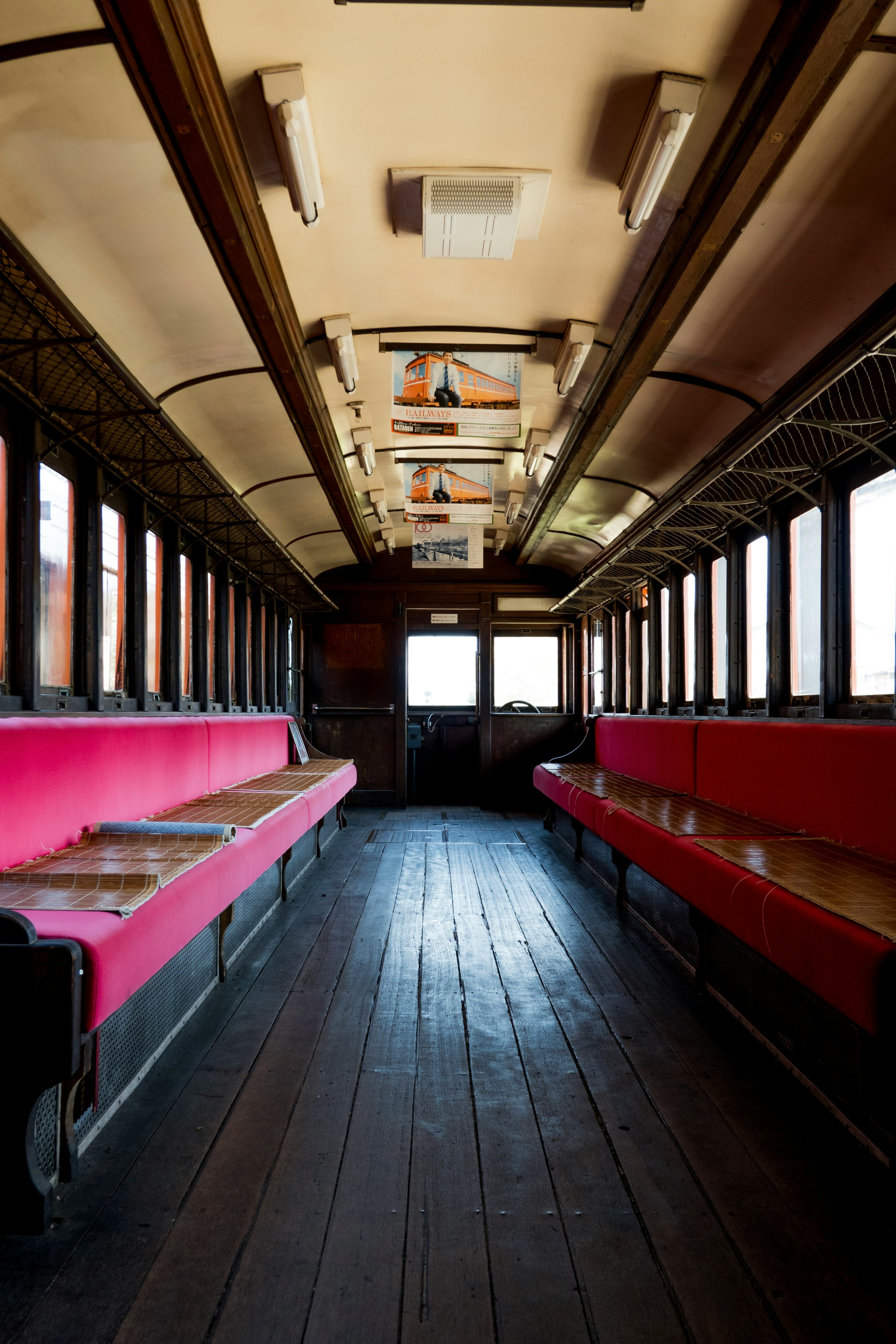 Interno di un vecchio vagone ferroviario con panche rosse e pavimento in legno