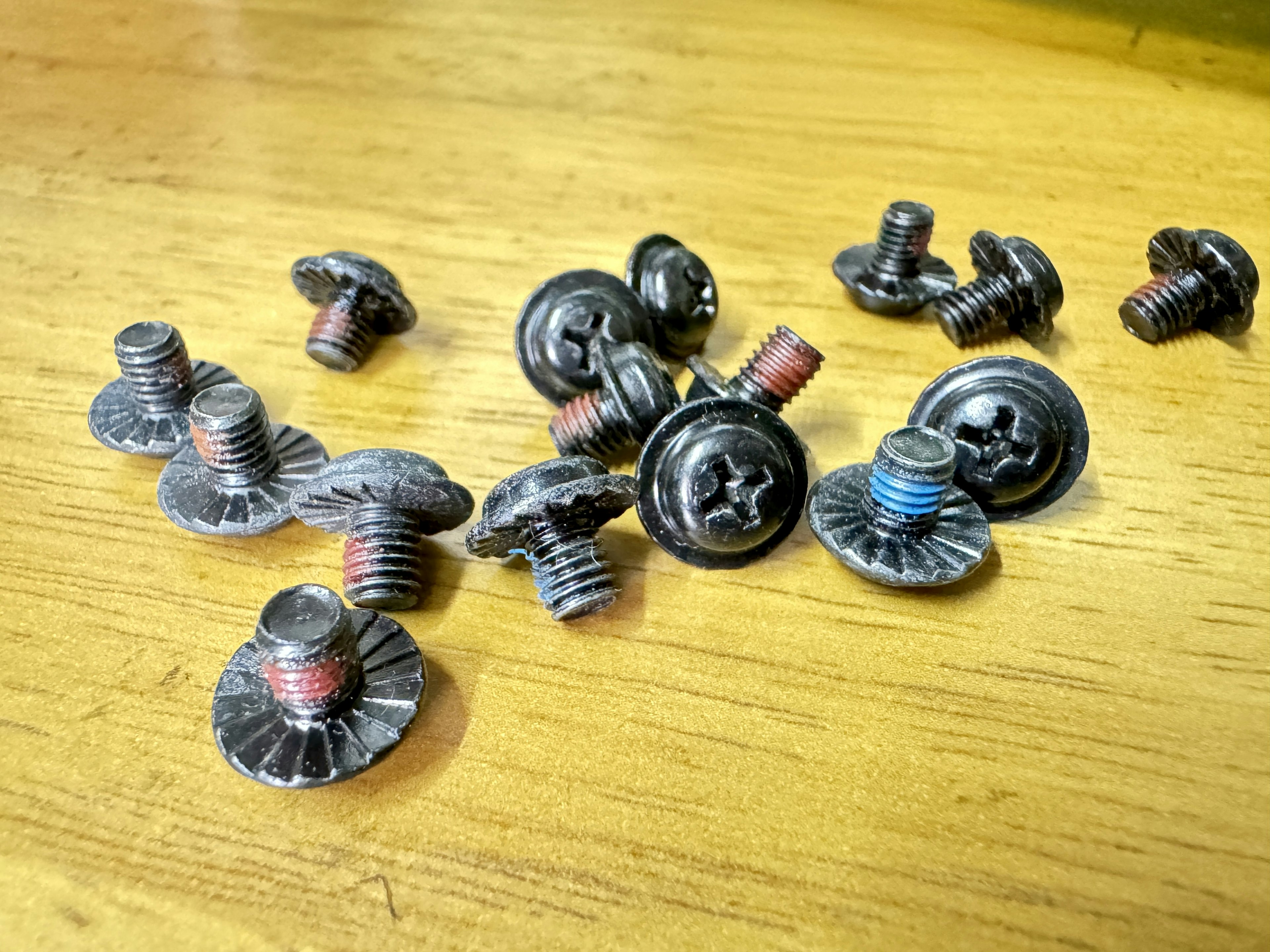 Black screws and bolts scattered on a wooden table