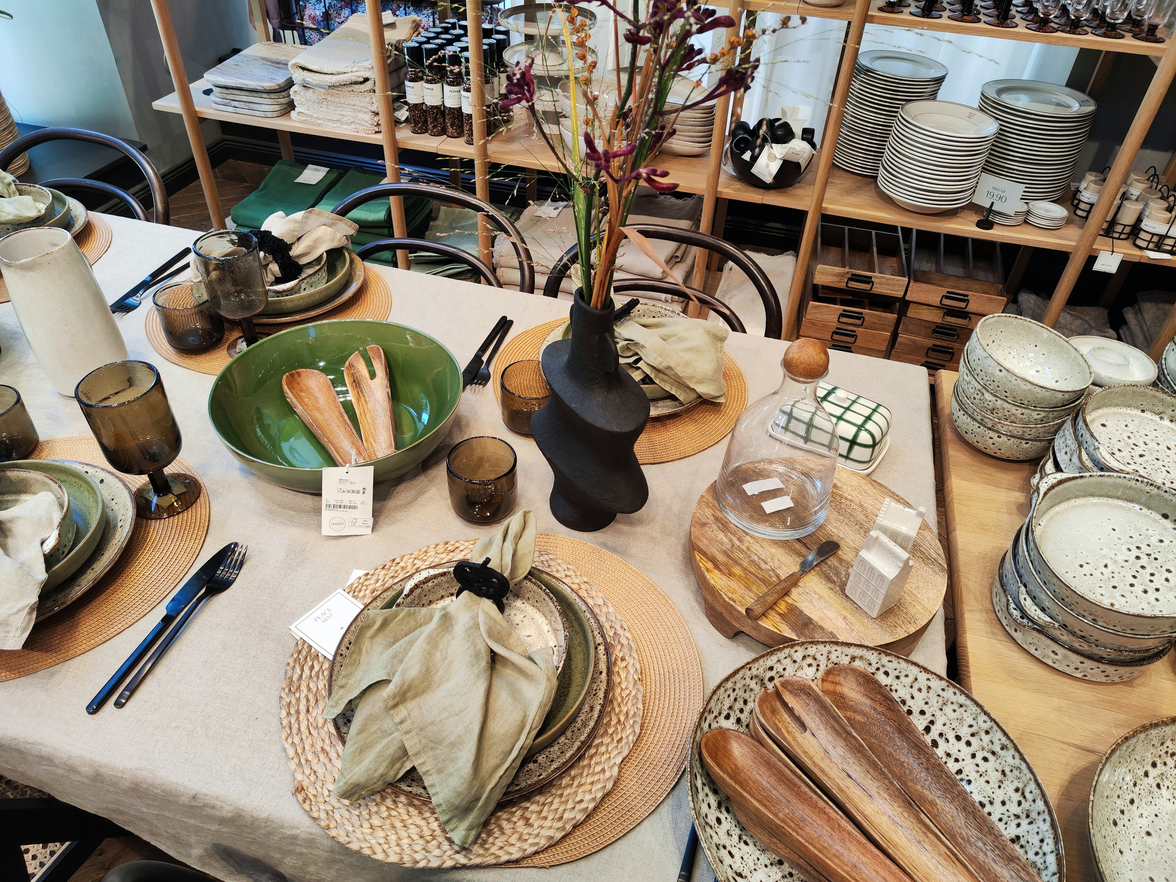 Una mesa de comedor bellamente dispuesta con varios platos y elementos decorativos que incluyen cuencos, vasos y utensilios