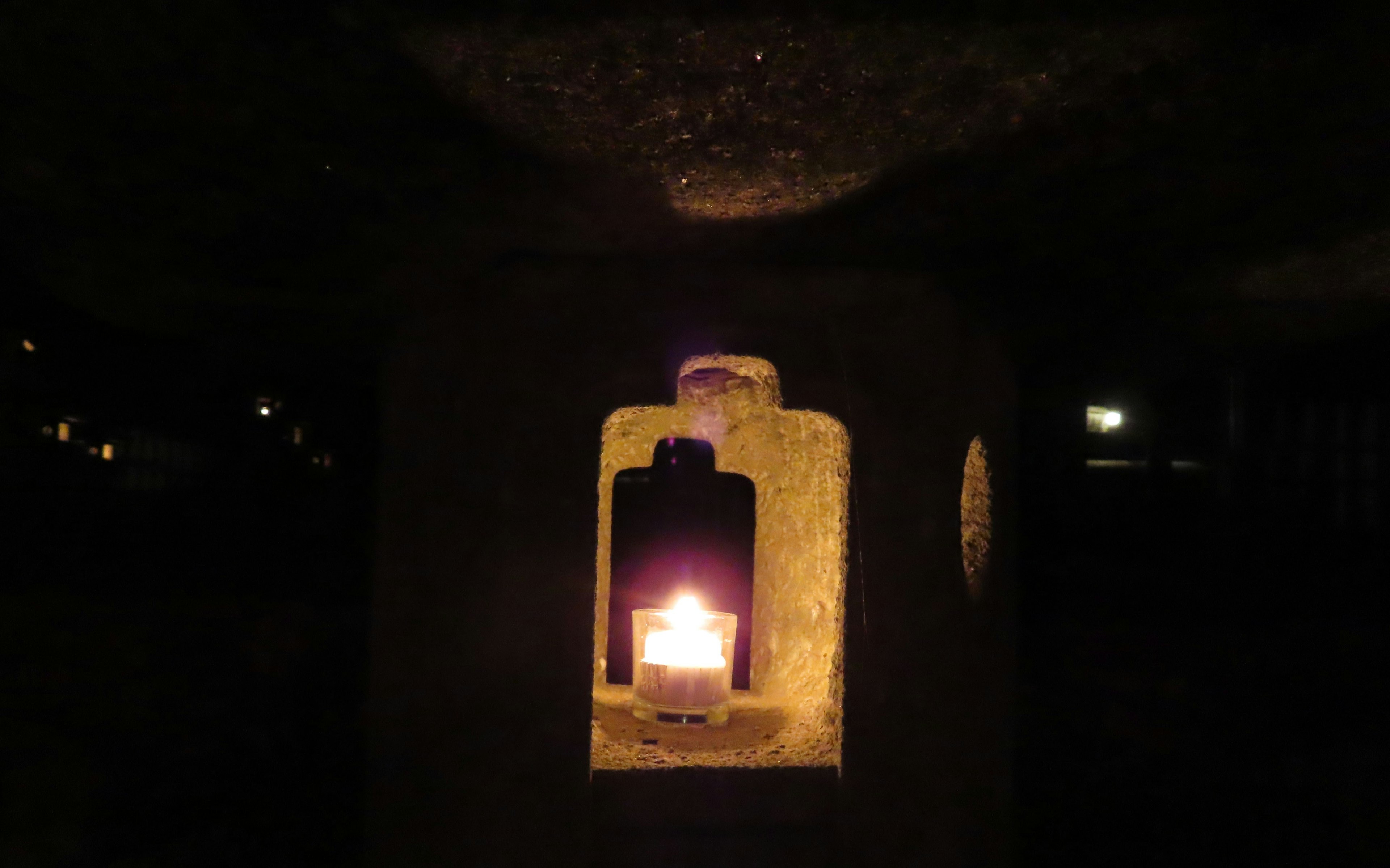 Candle lit inside a stone lantern in a dimly lit setting