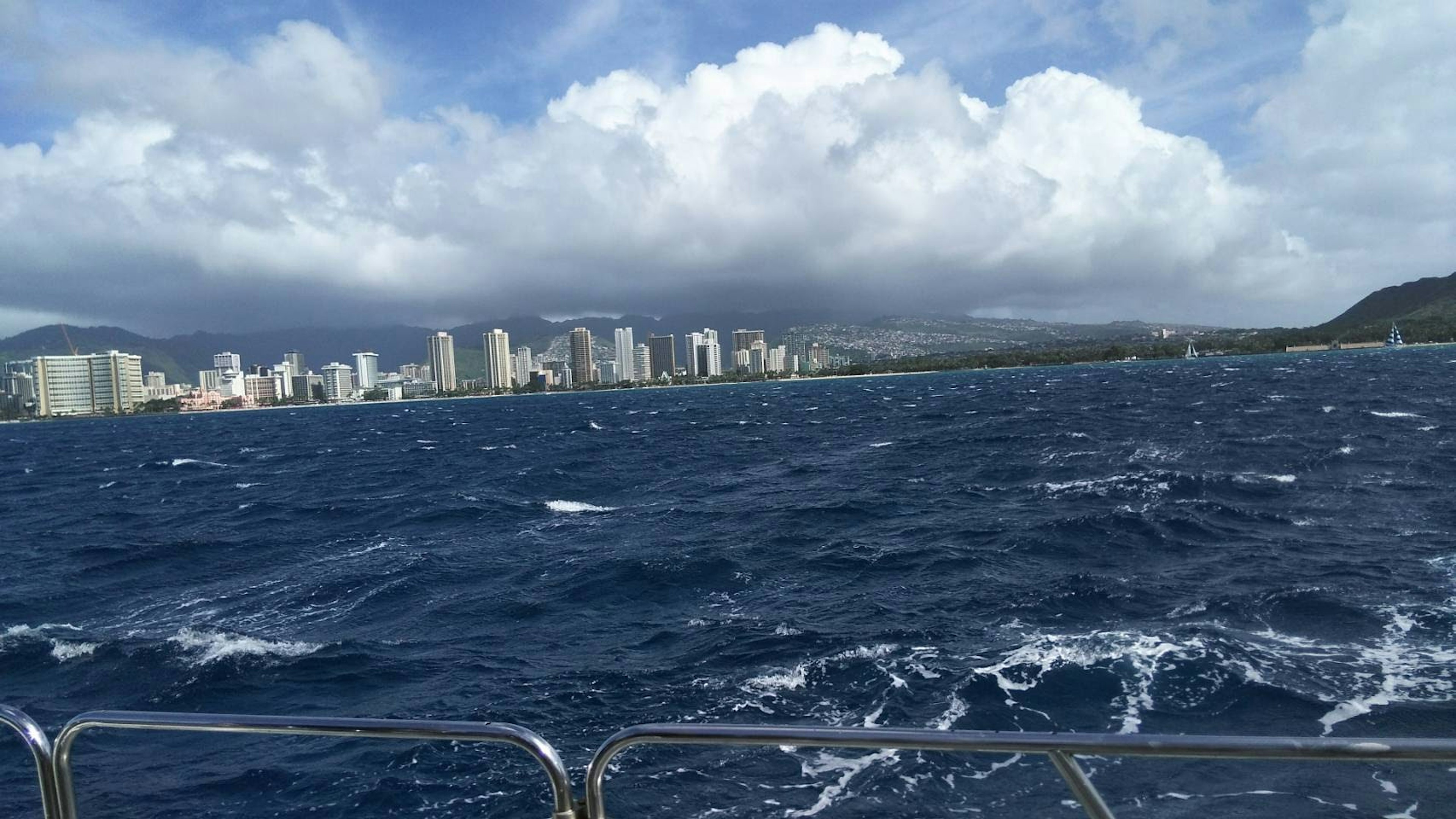 View of Honolulu coastline in Hawaii blue ocean and white waves cloudy sky in the background