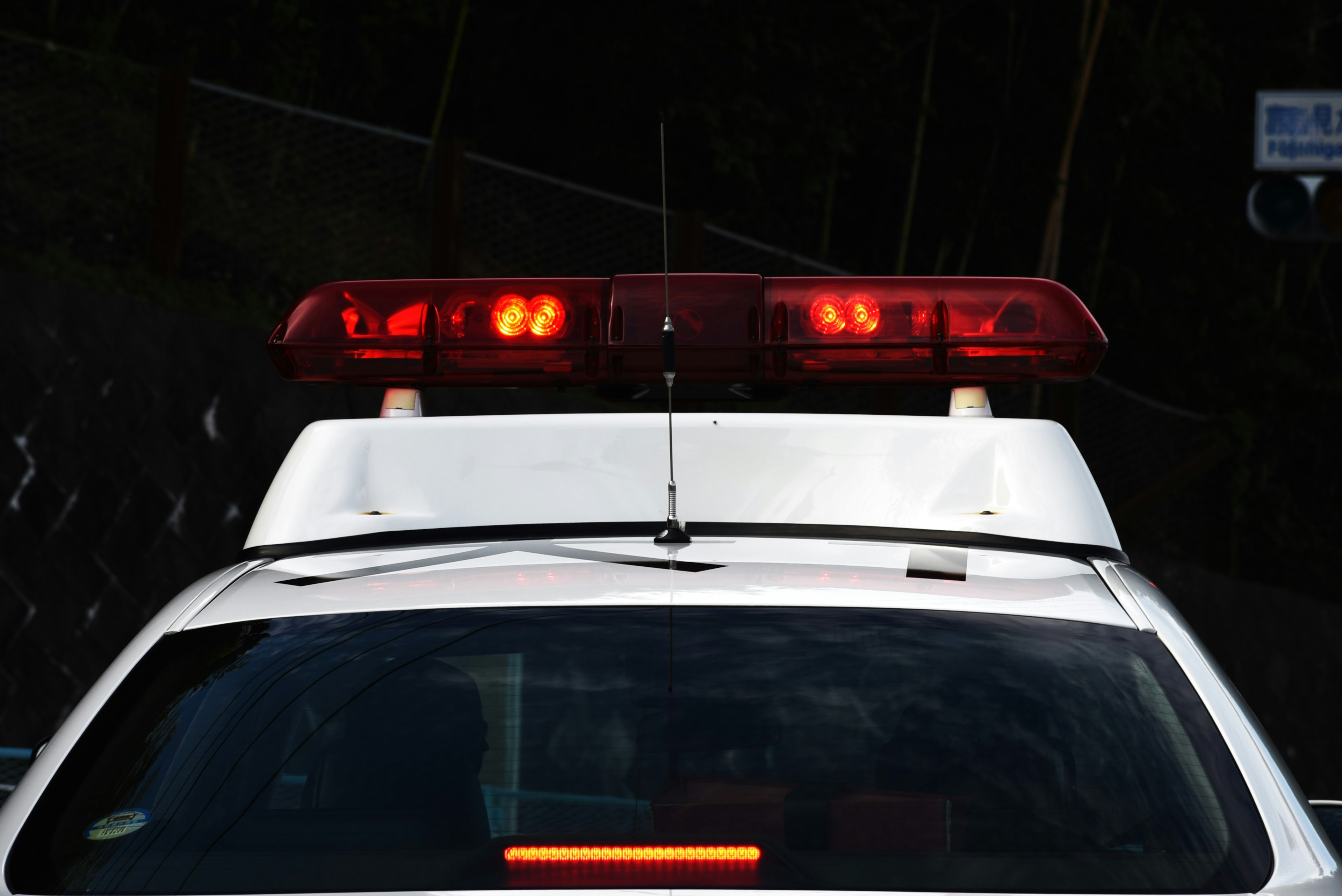 Vista trasera de un coche de policía con luces rojas activadas