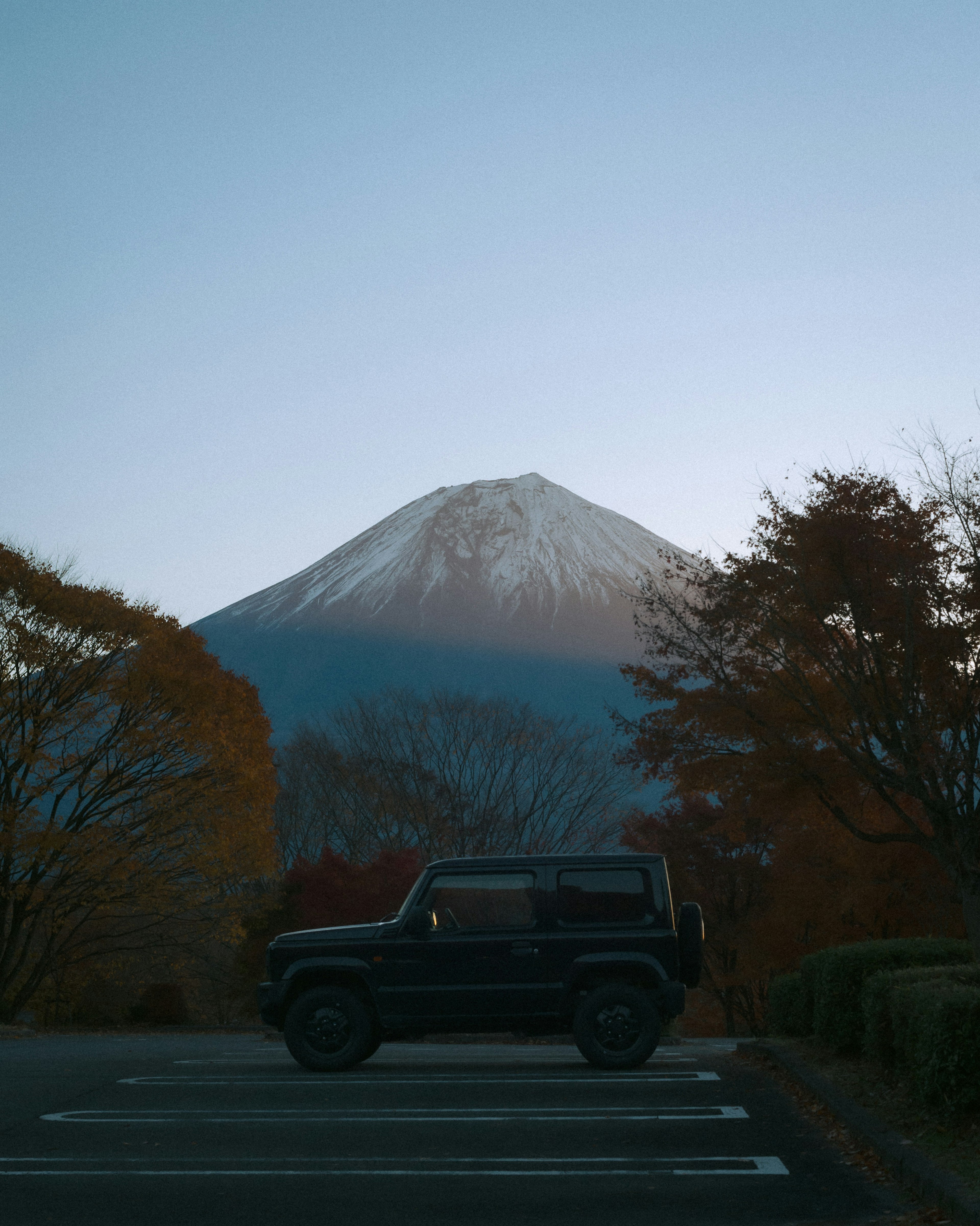 富士山の背景にある黒いSUVと紅葉した木々