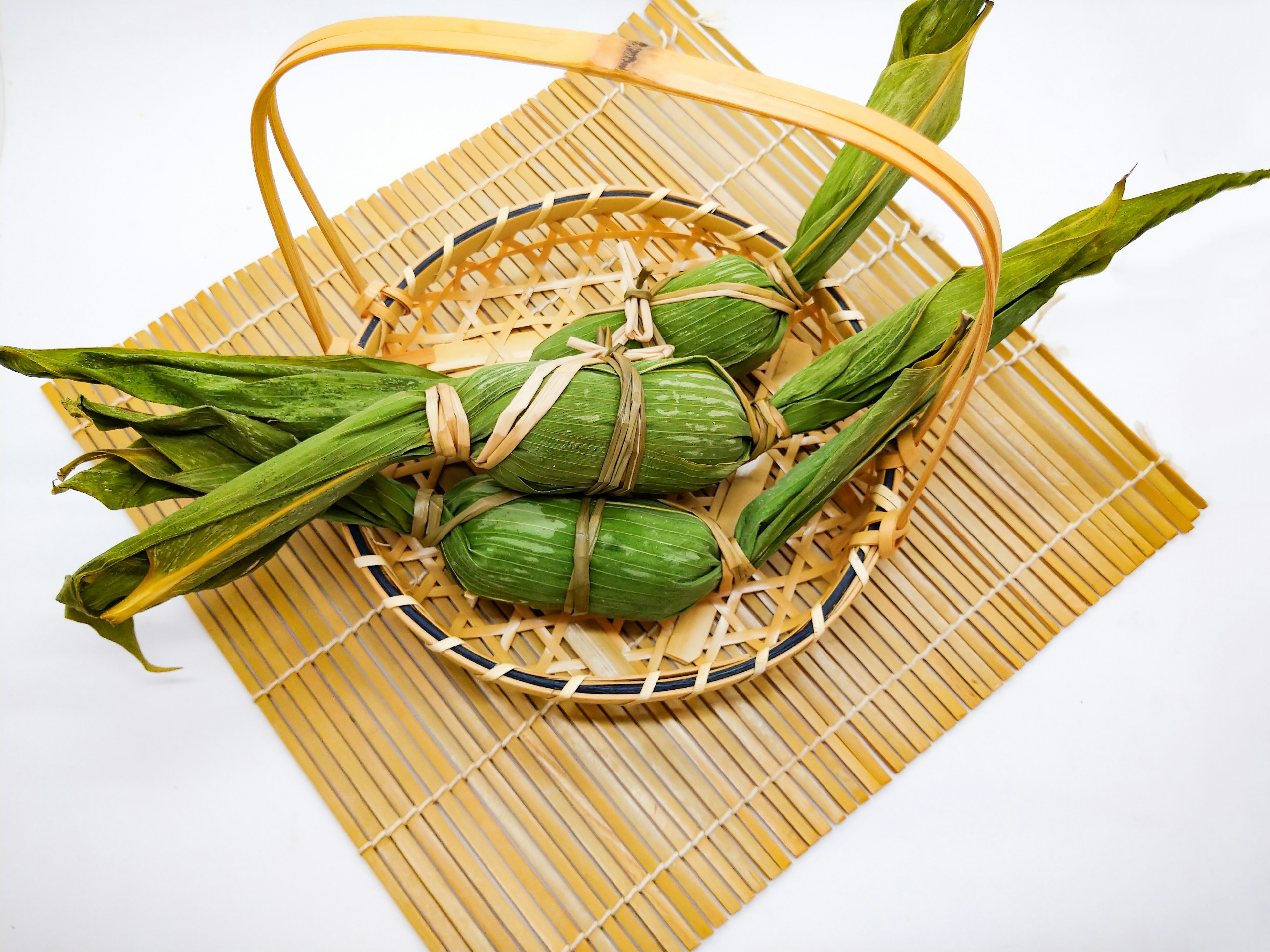 Comida envuelta en hojas verdes colocada en una cesta con hojas de bambú