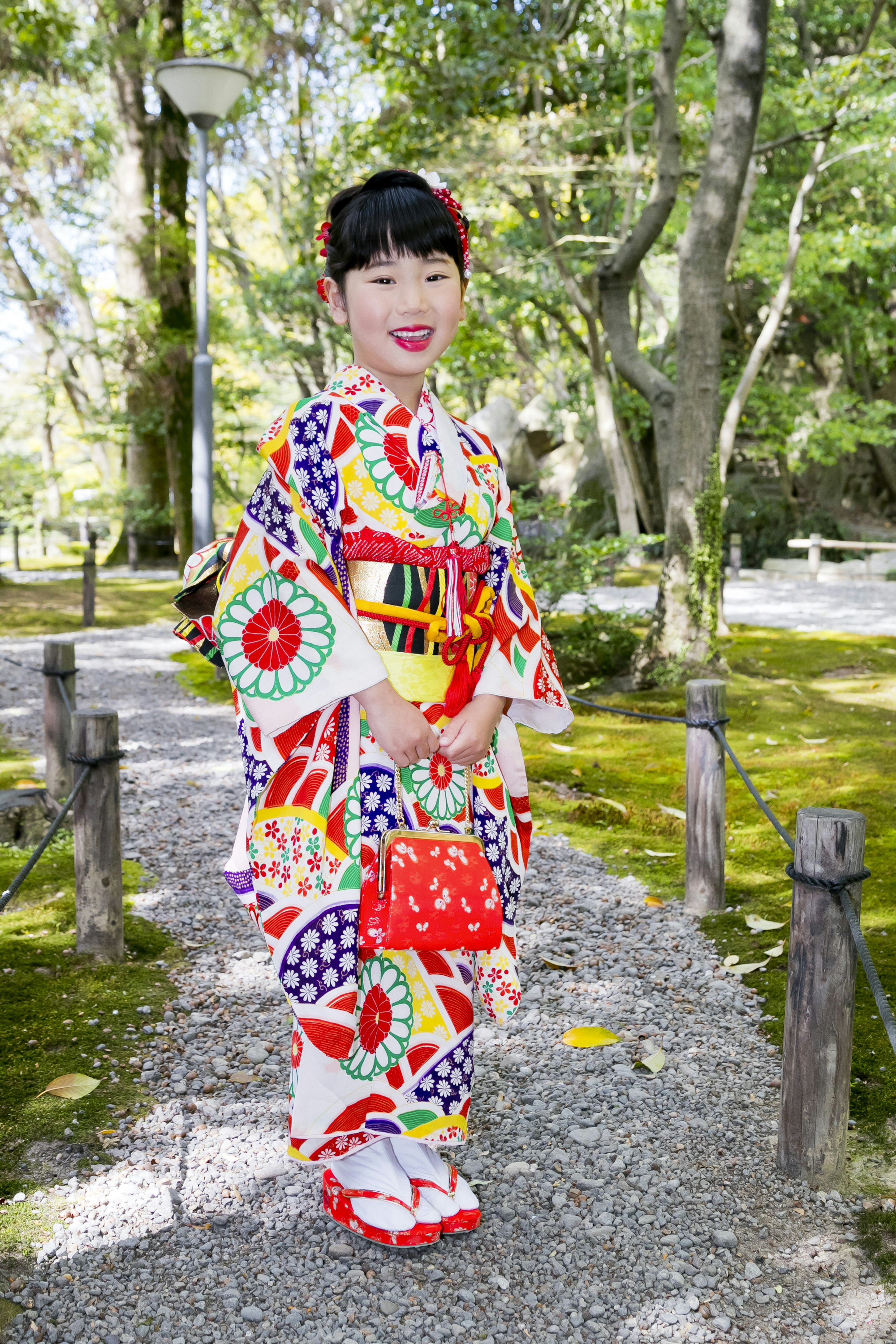 一個穿著彩色和服的孩子站在公園小路上