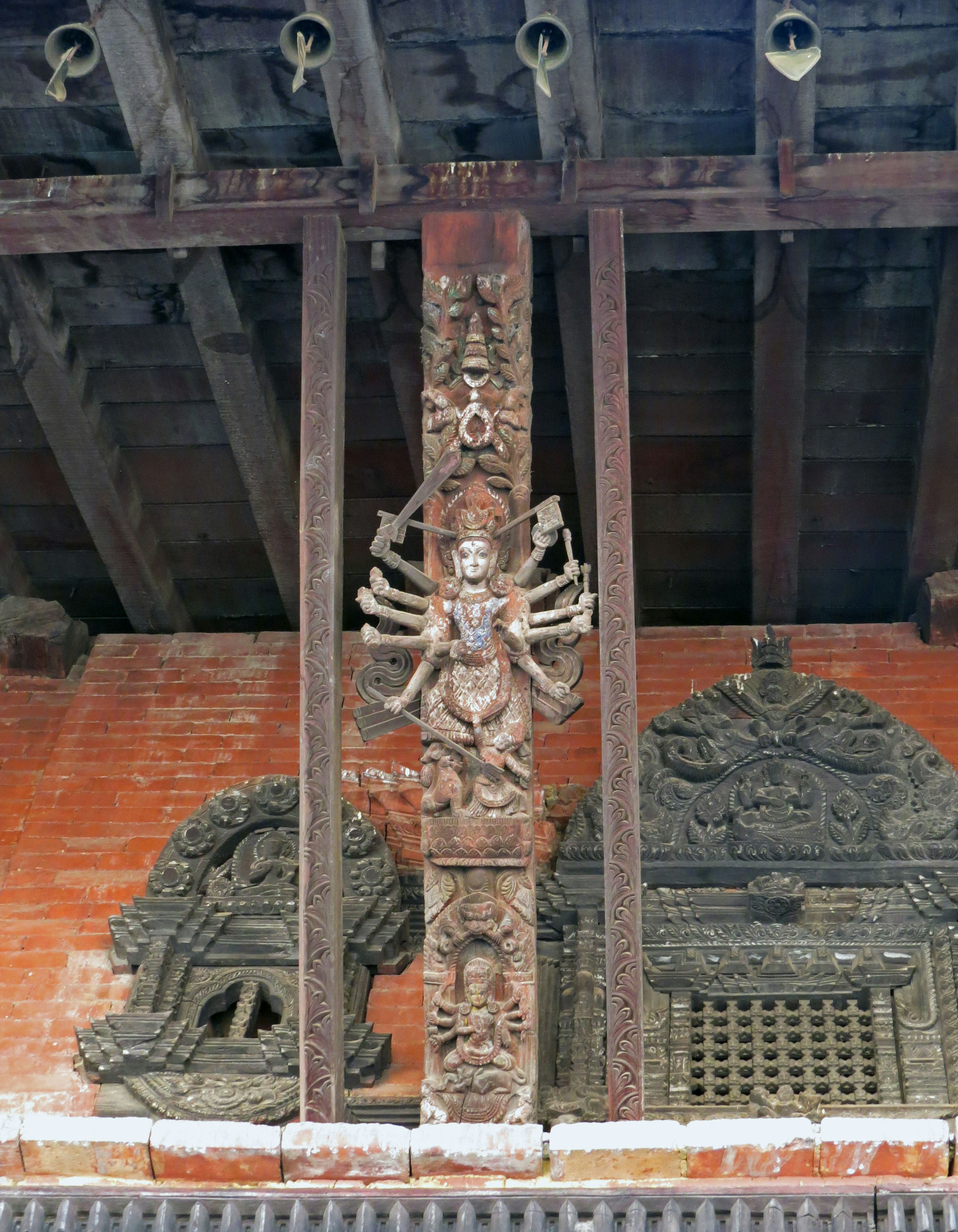 Bâtiment avec un pilier en bois sculpté de manière complexe et un mur en brique rouge