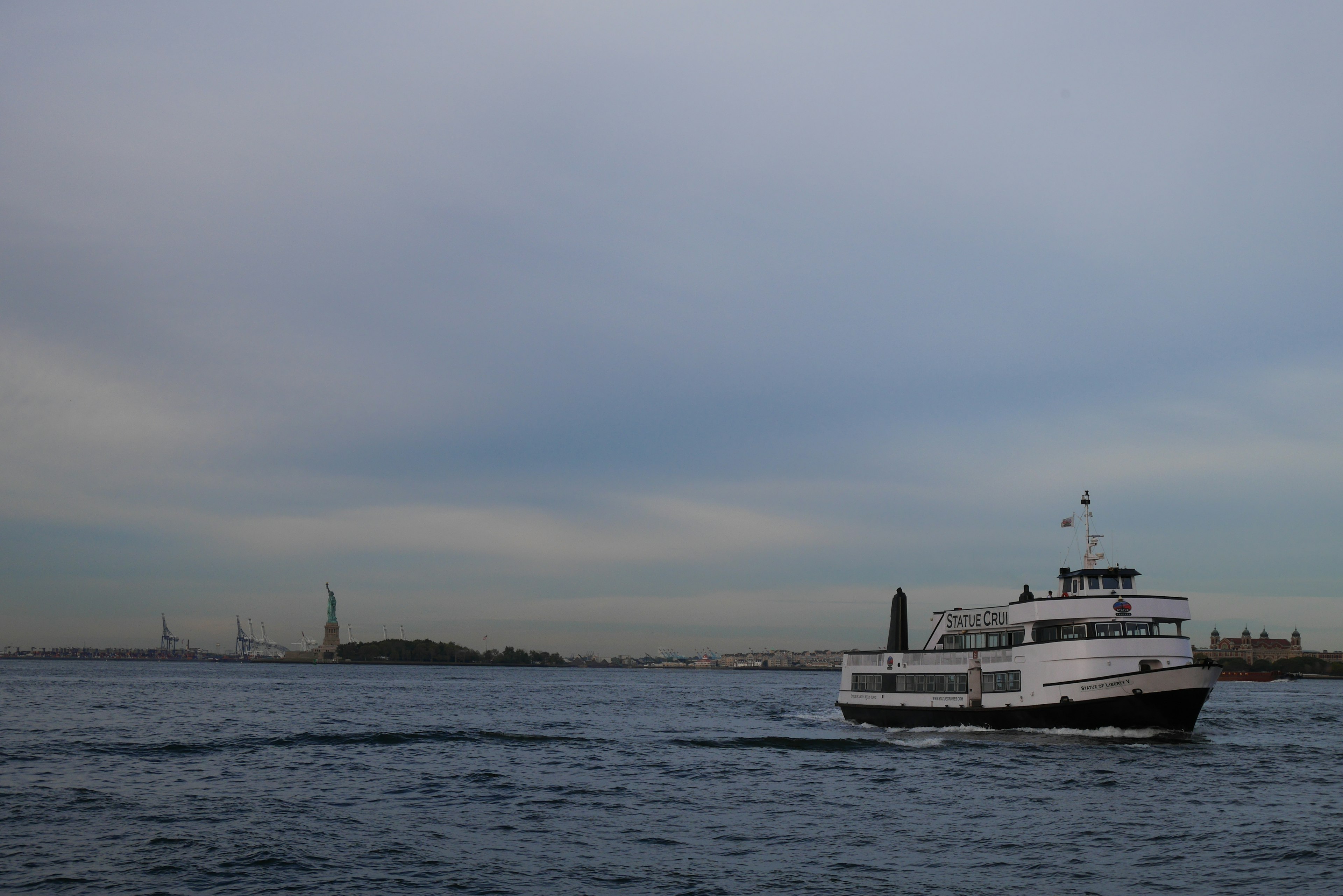 A black and white ferry navigating the water with distant landmarks