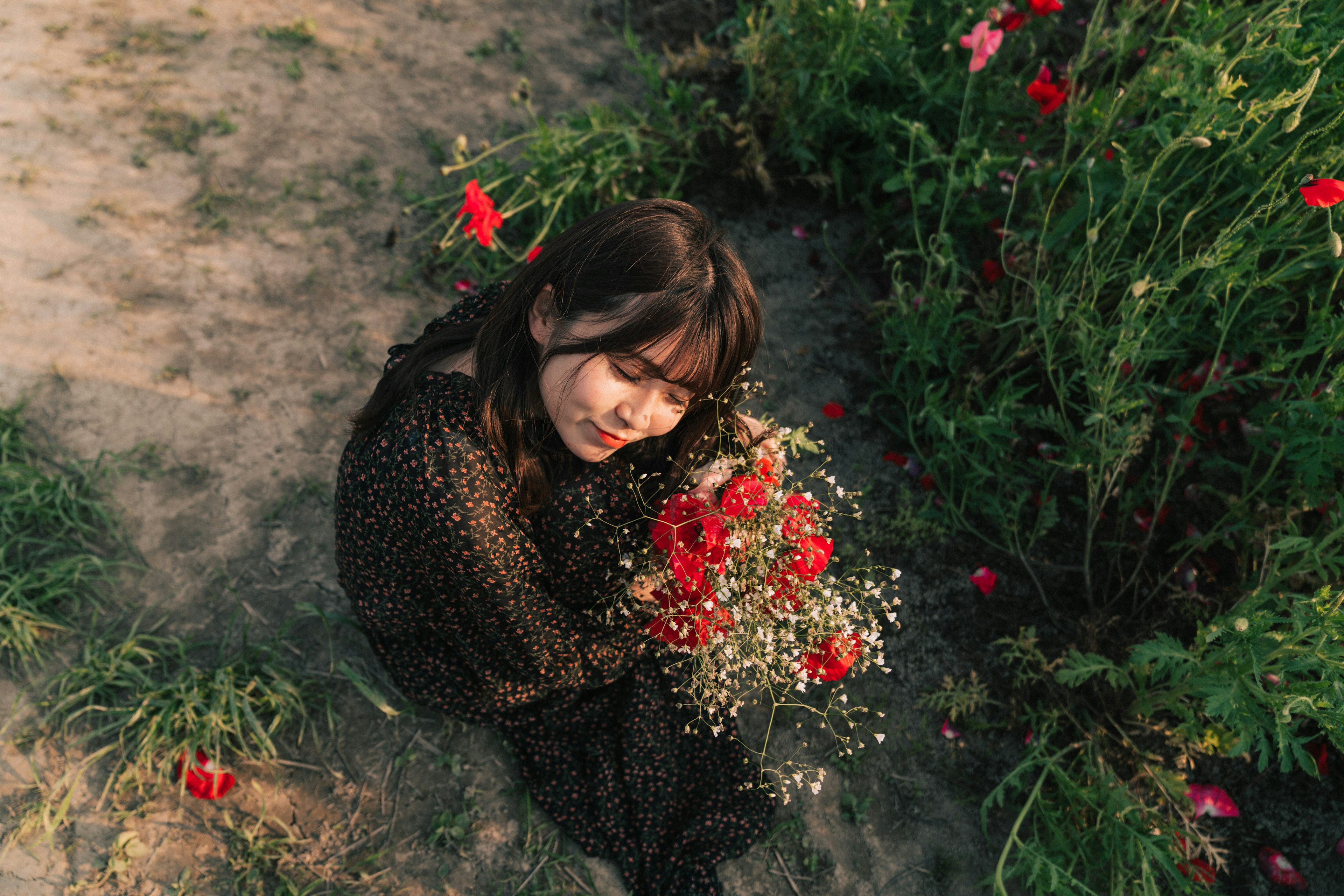 Una mujer sonriendo mientras sostiene un ramo de flores en un campo