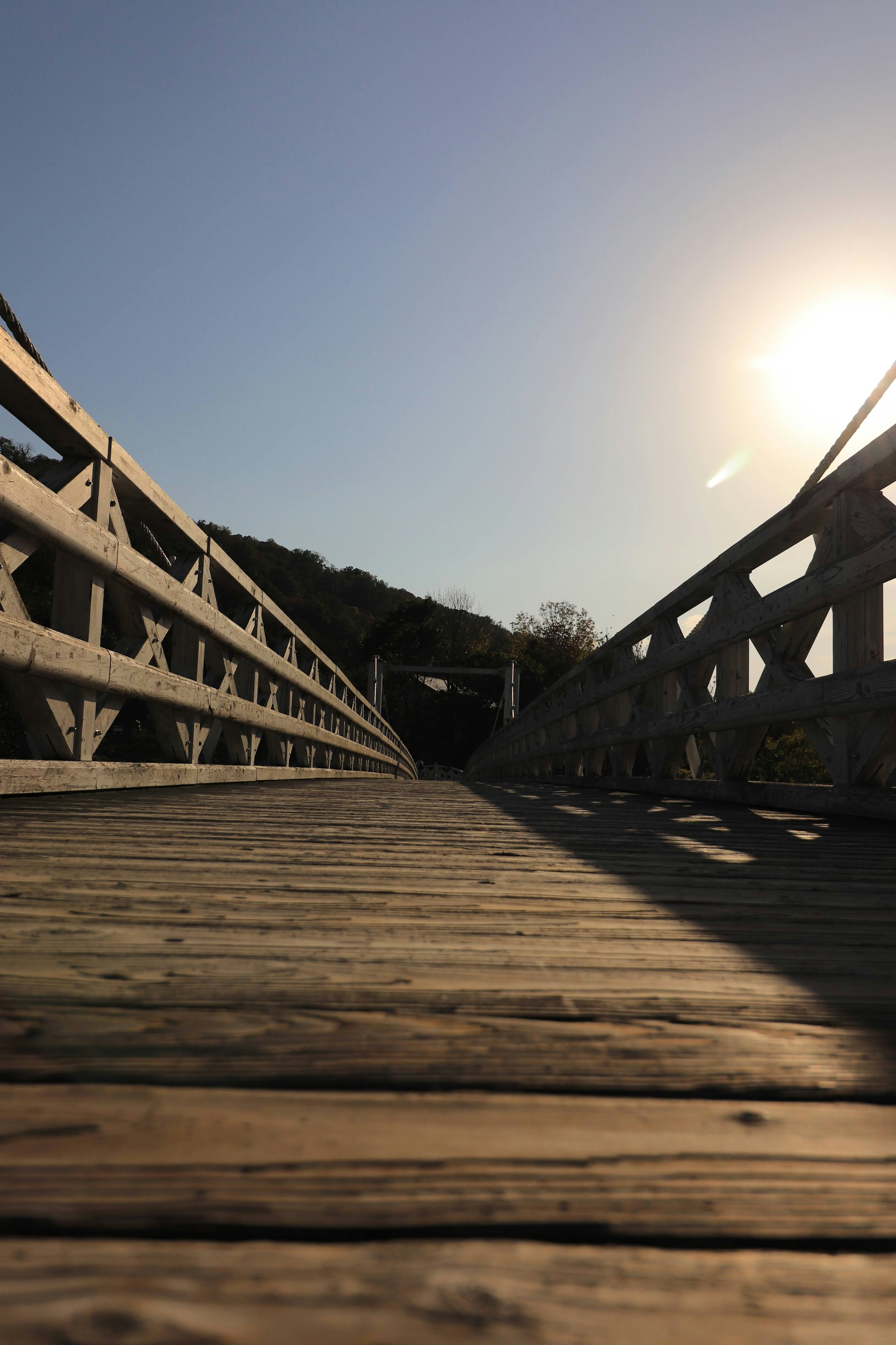 Niedrigwinkelansicht einer Holzbrücke mit Sonnenuntergang im Hintergrund