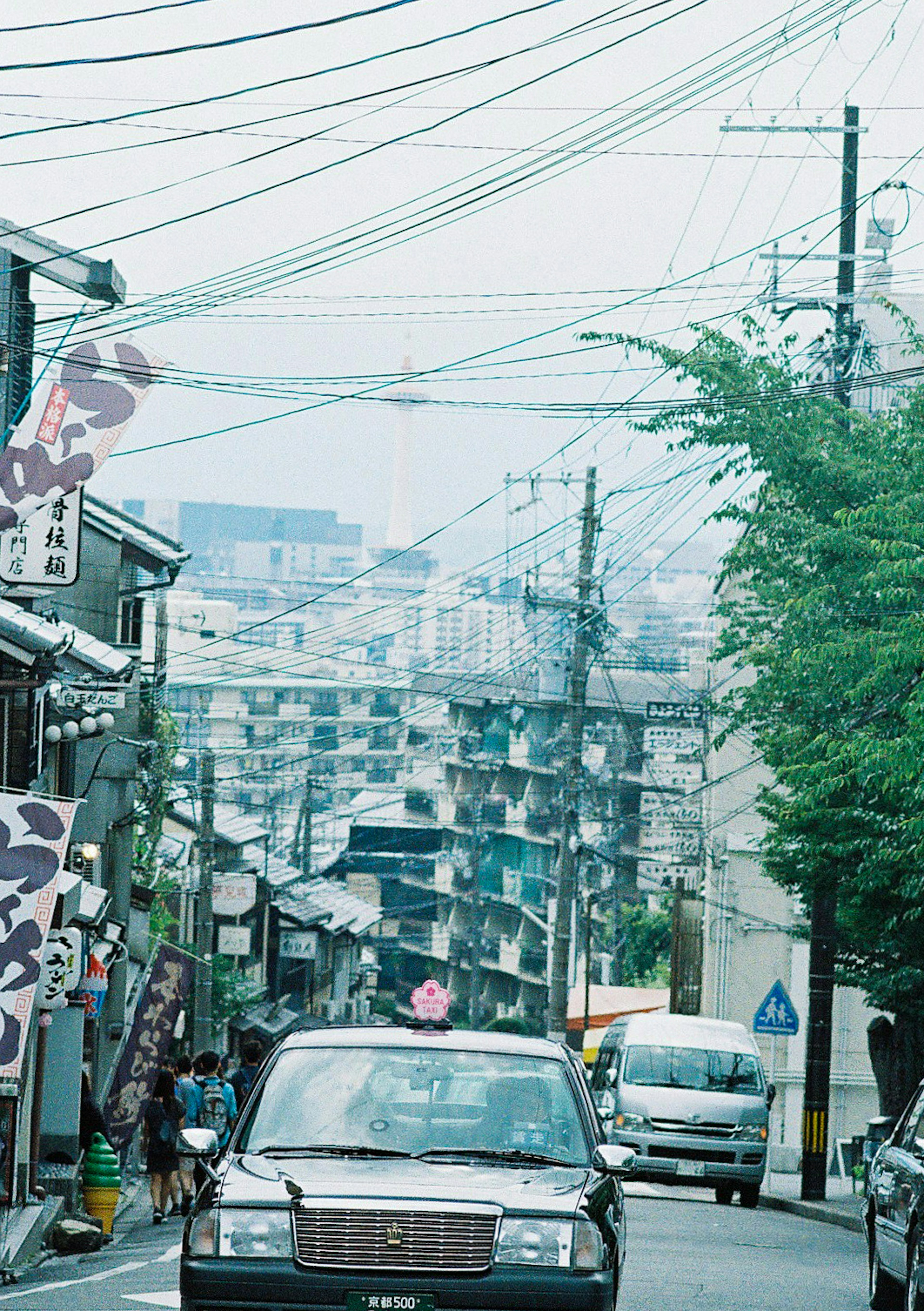 Narrow street with a car and utility poles under a cloudy sky