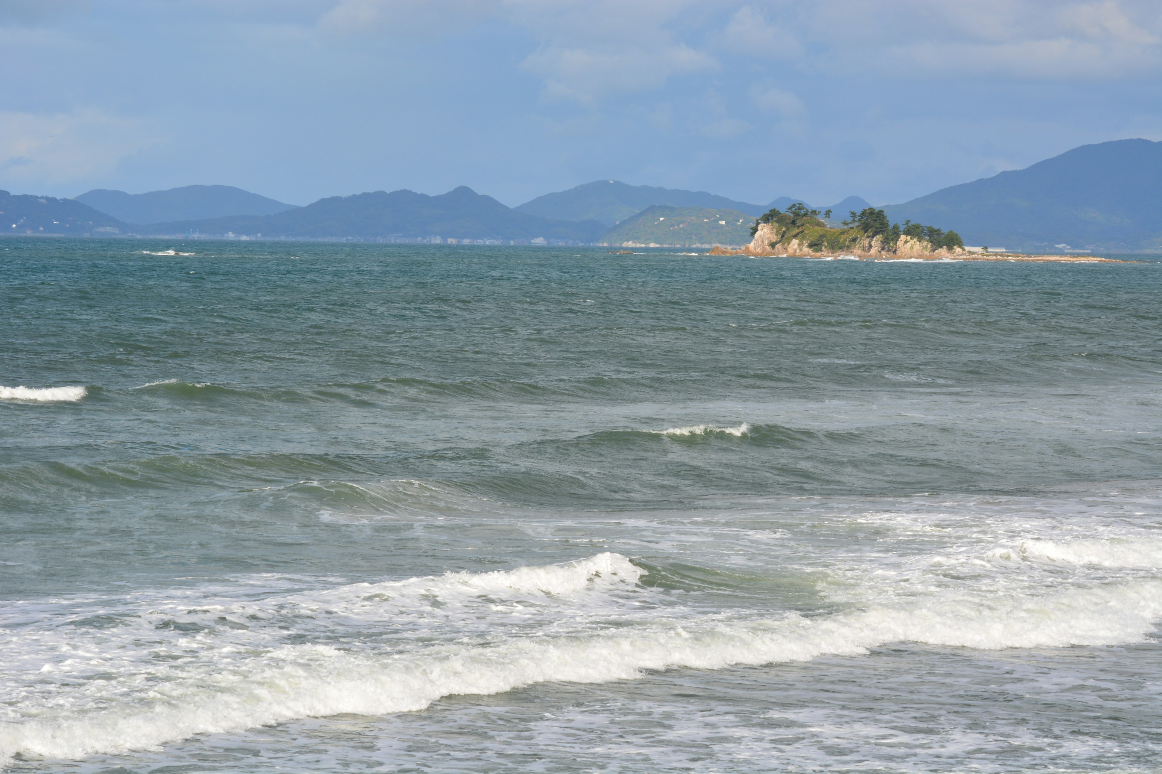 Vue expansive de la mer bleue avec des vagues petite île au loin