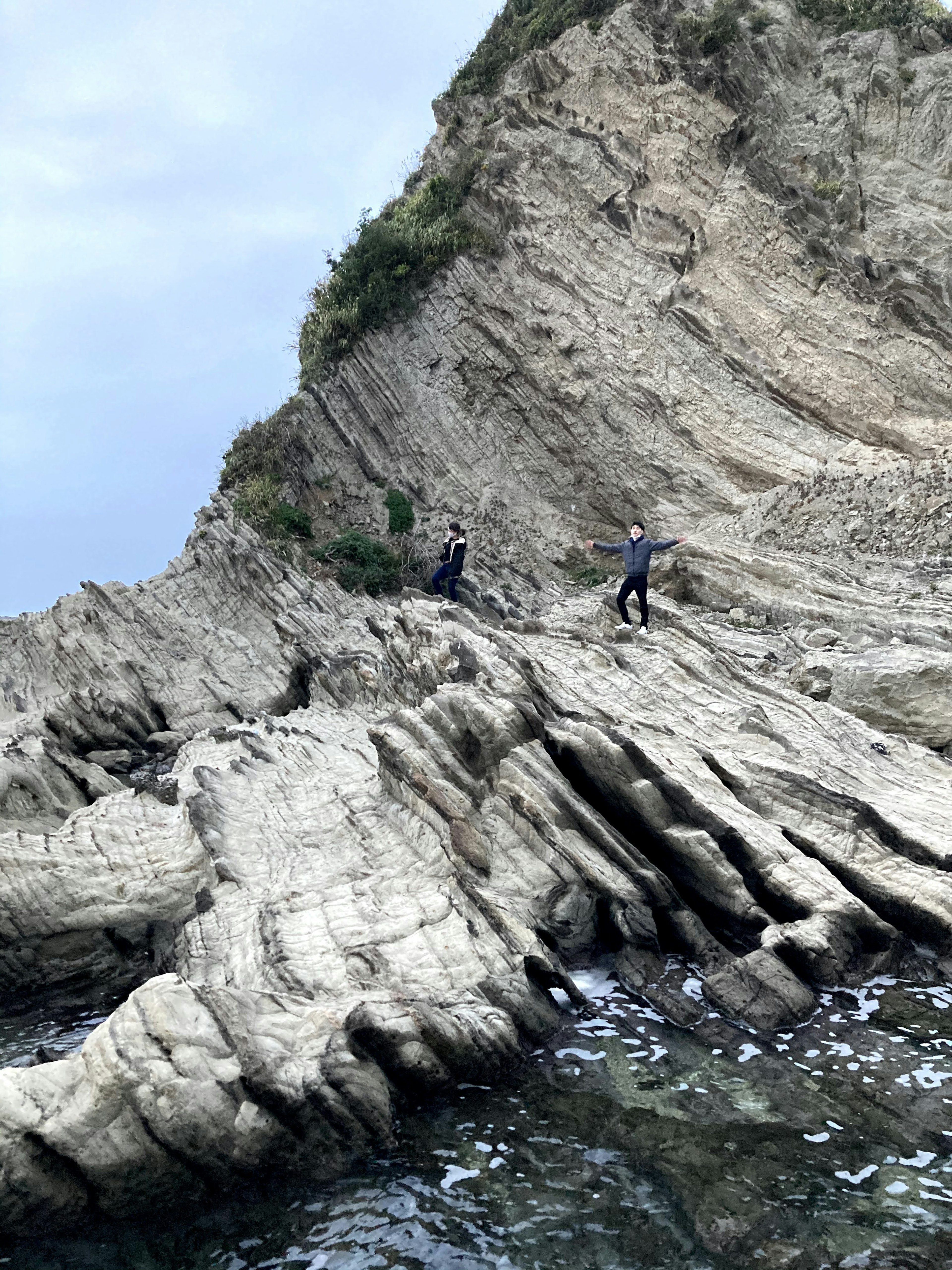 人们在陡峭悬崖的岩石海岸上行走