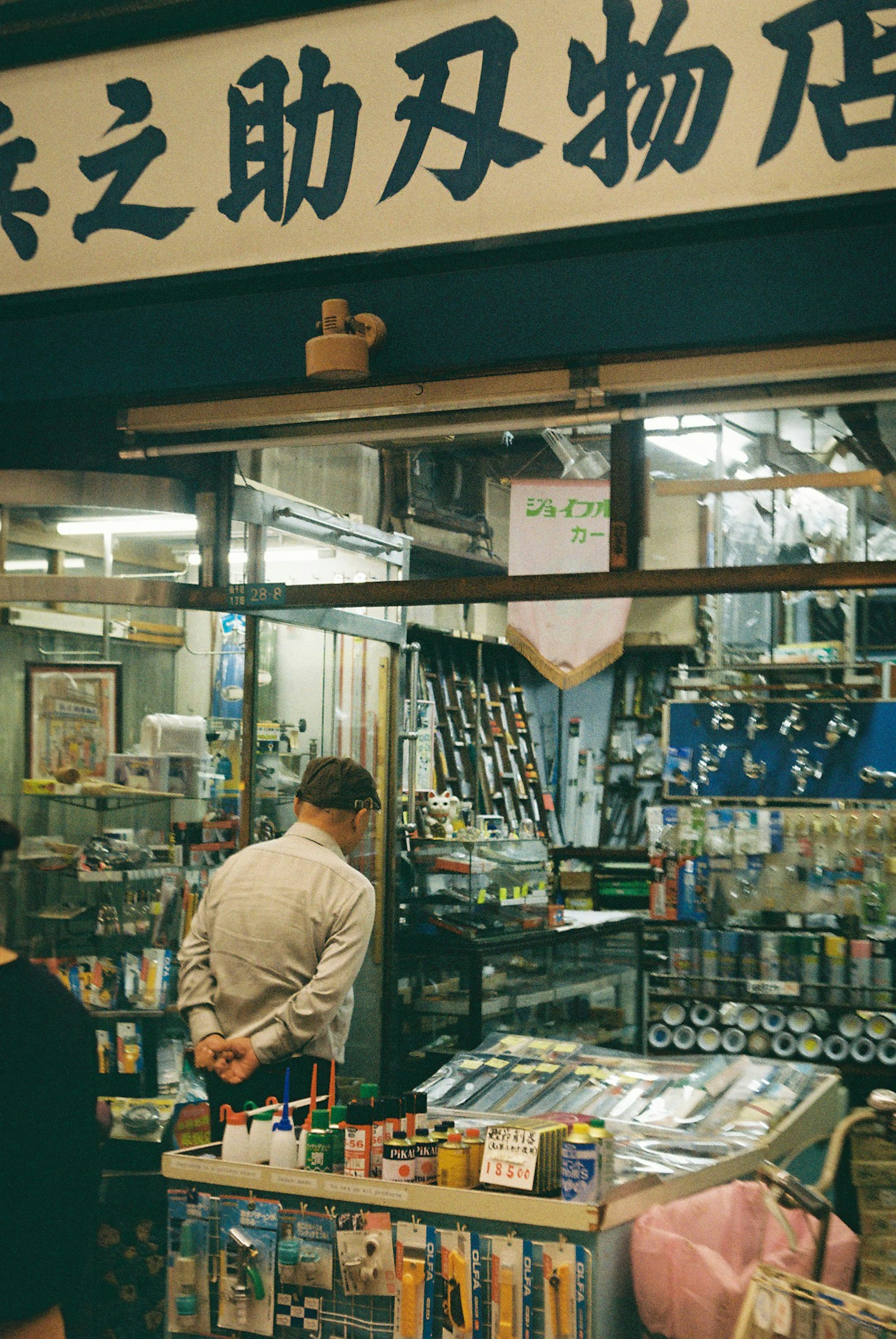 伝統的な雑貨店の外観で、店主が商品を見ている様子