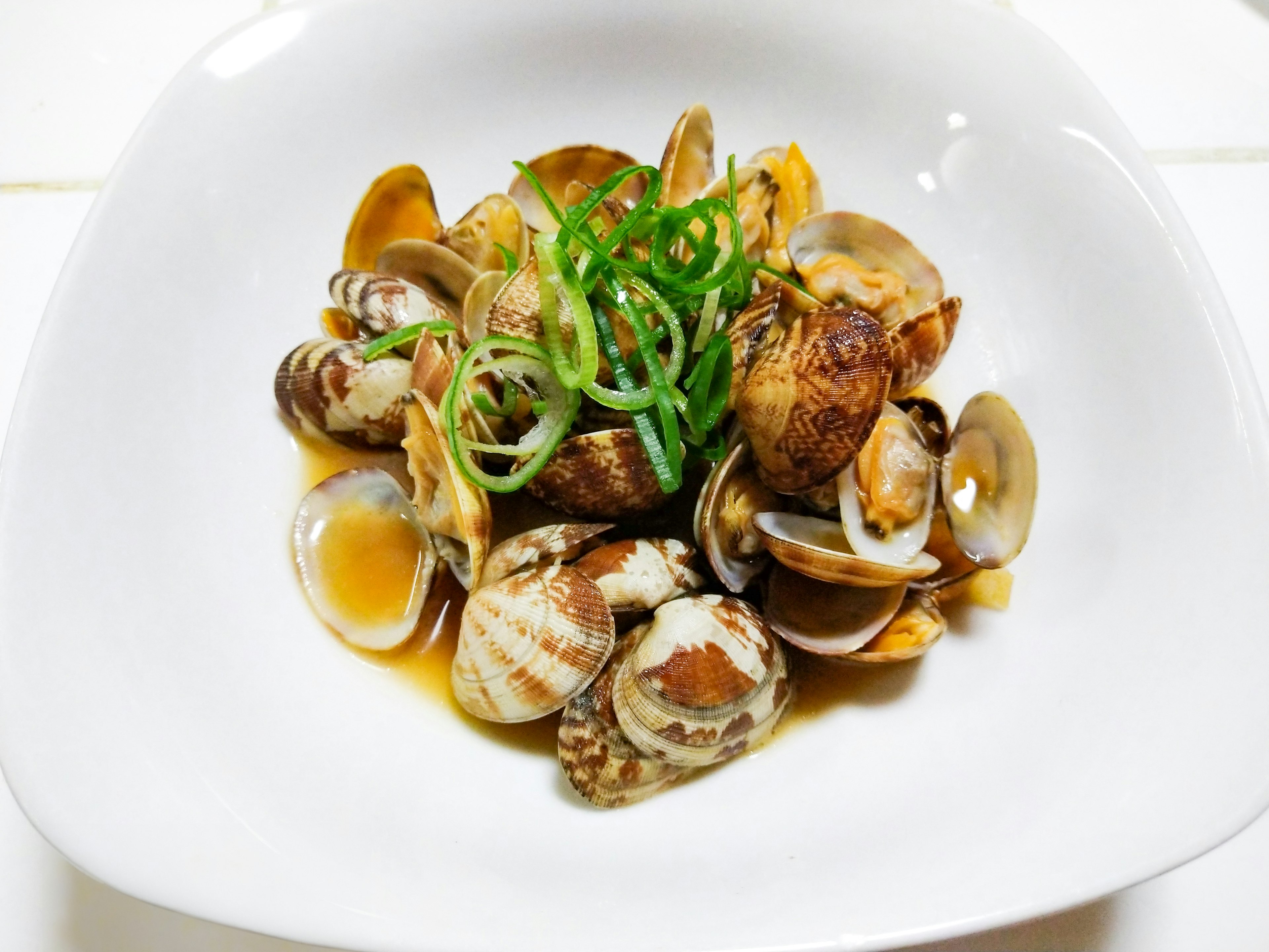 Un plato de almejas decorado con cebollino