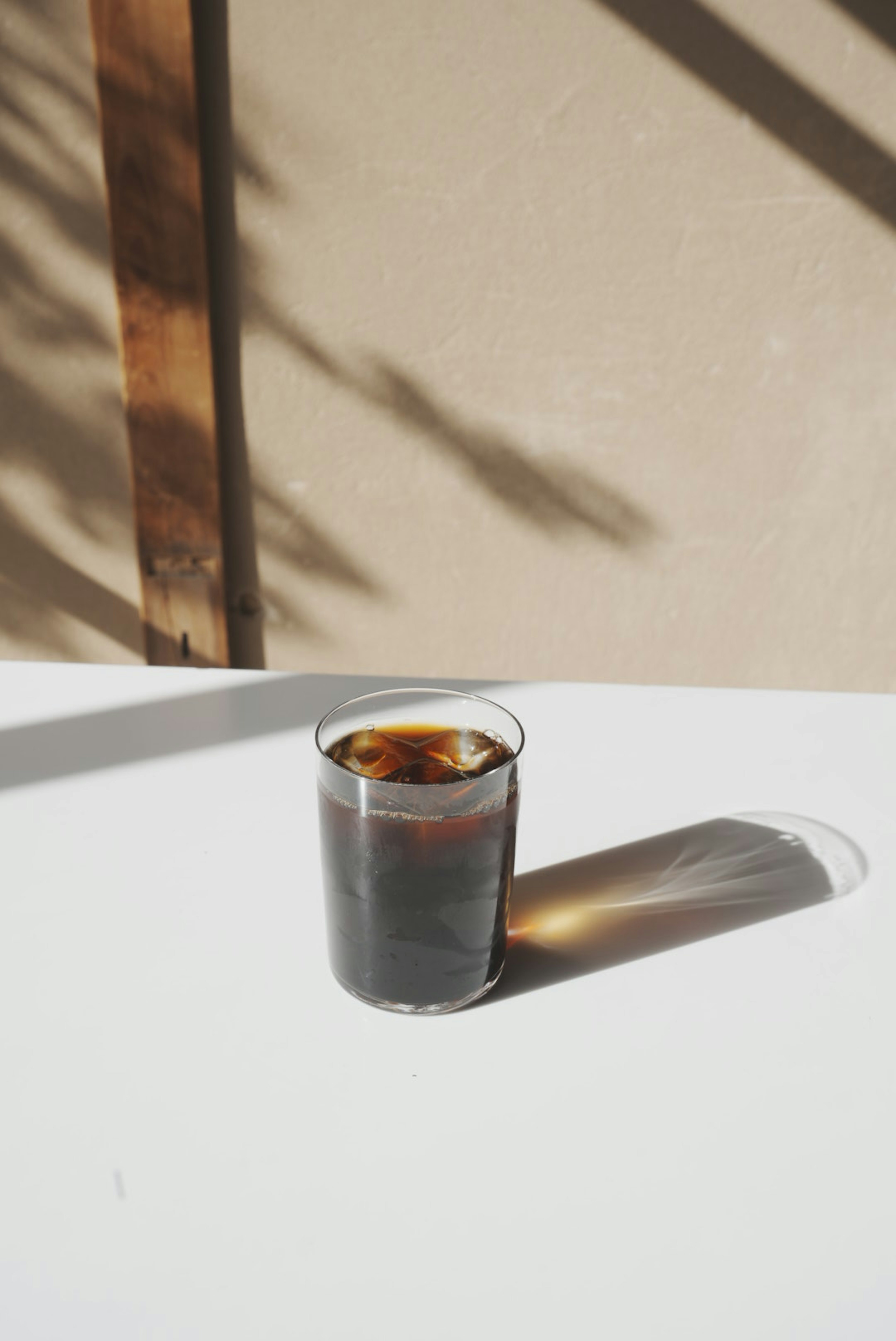 A glass of iced coffee on a table with a shadow