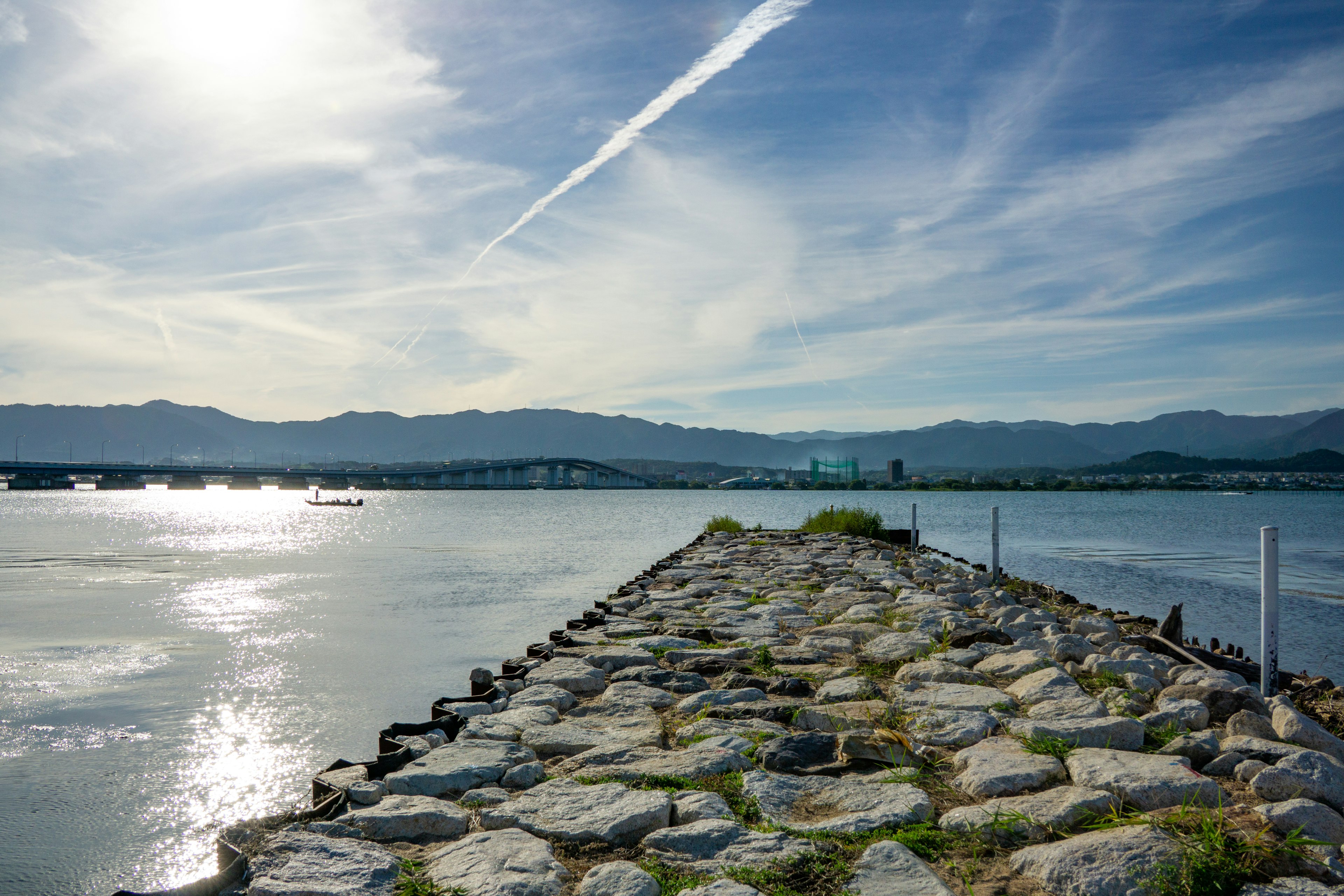 Camino de piedras a lo largo de un lago tranquilo con cielo azul