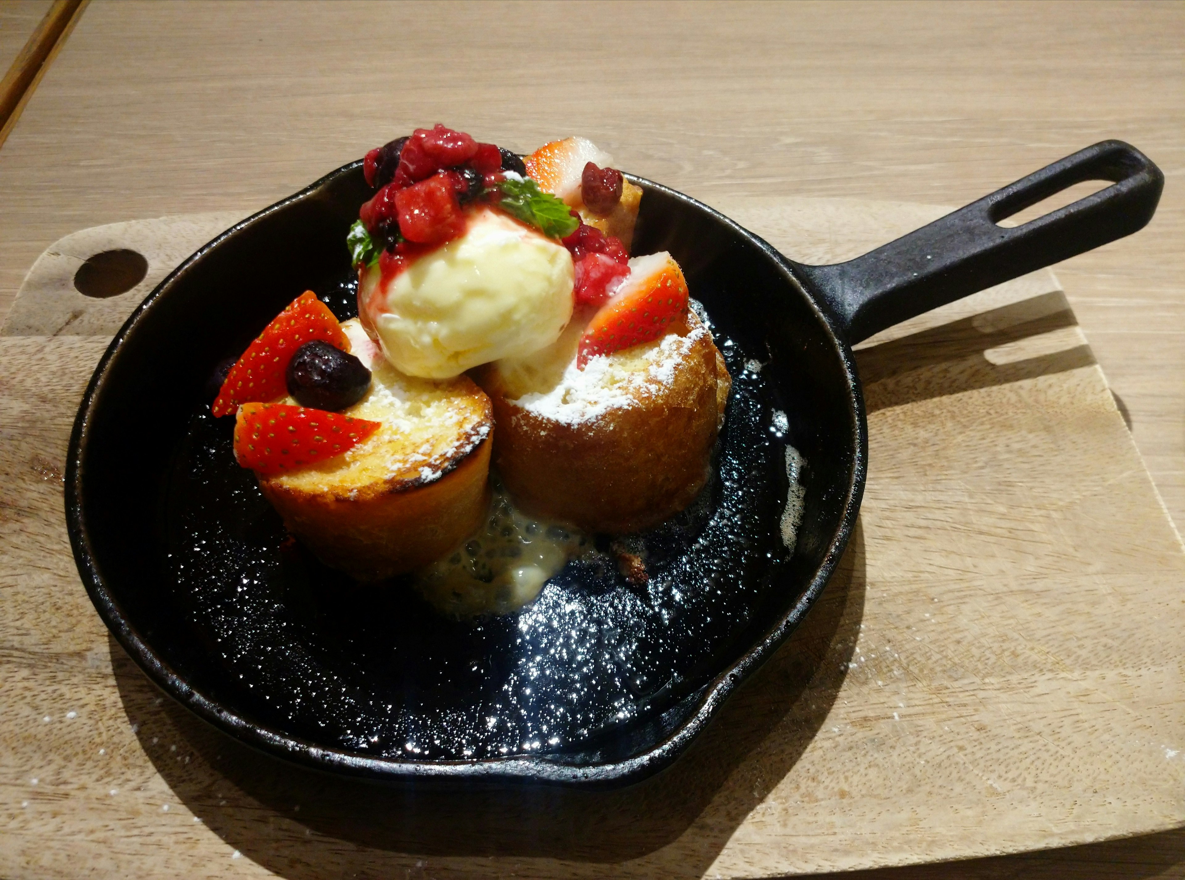 Dessert mit Früchten und Eis auf einer heißen Pfanne