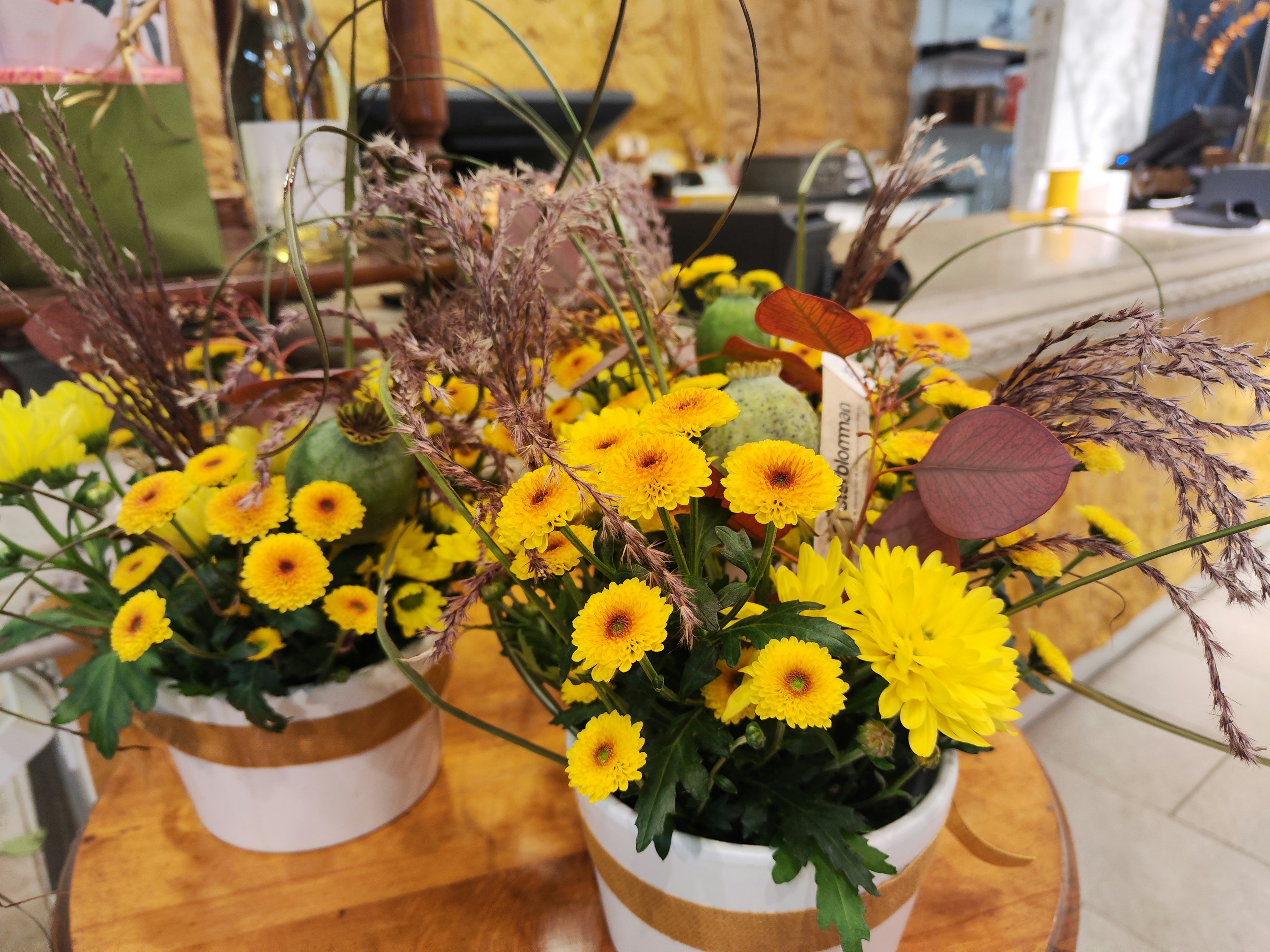 Blumenarrangement mit leuchtend gelben Blumen und grünen Blättern in dekorativen Töpfen