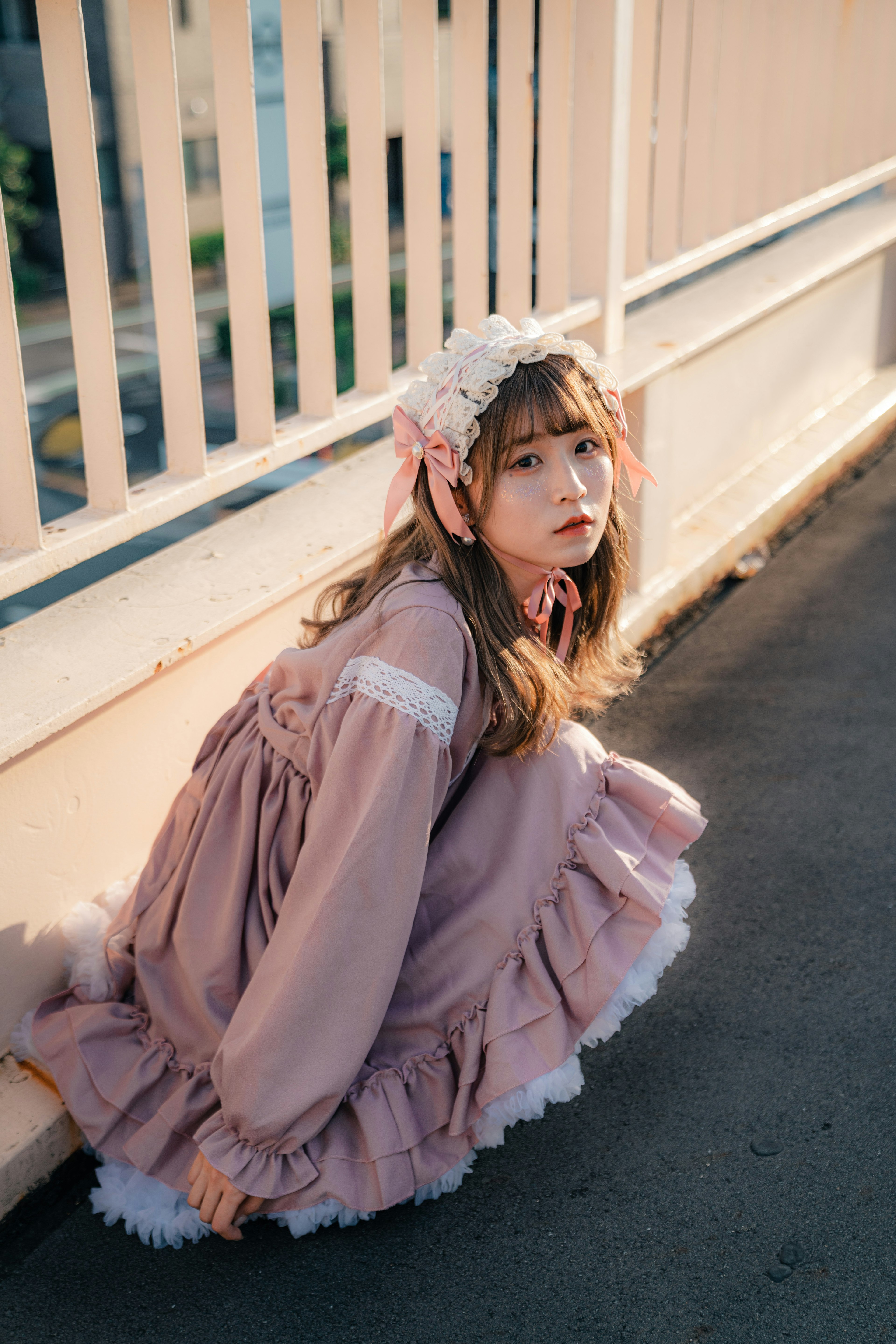 A girl wearing a light pink dress crouching with a floral headband