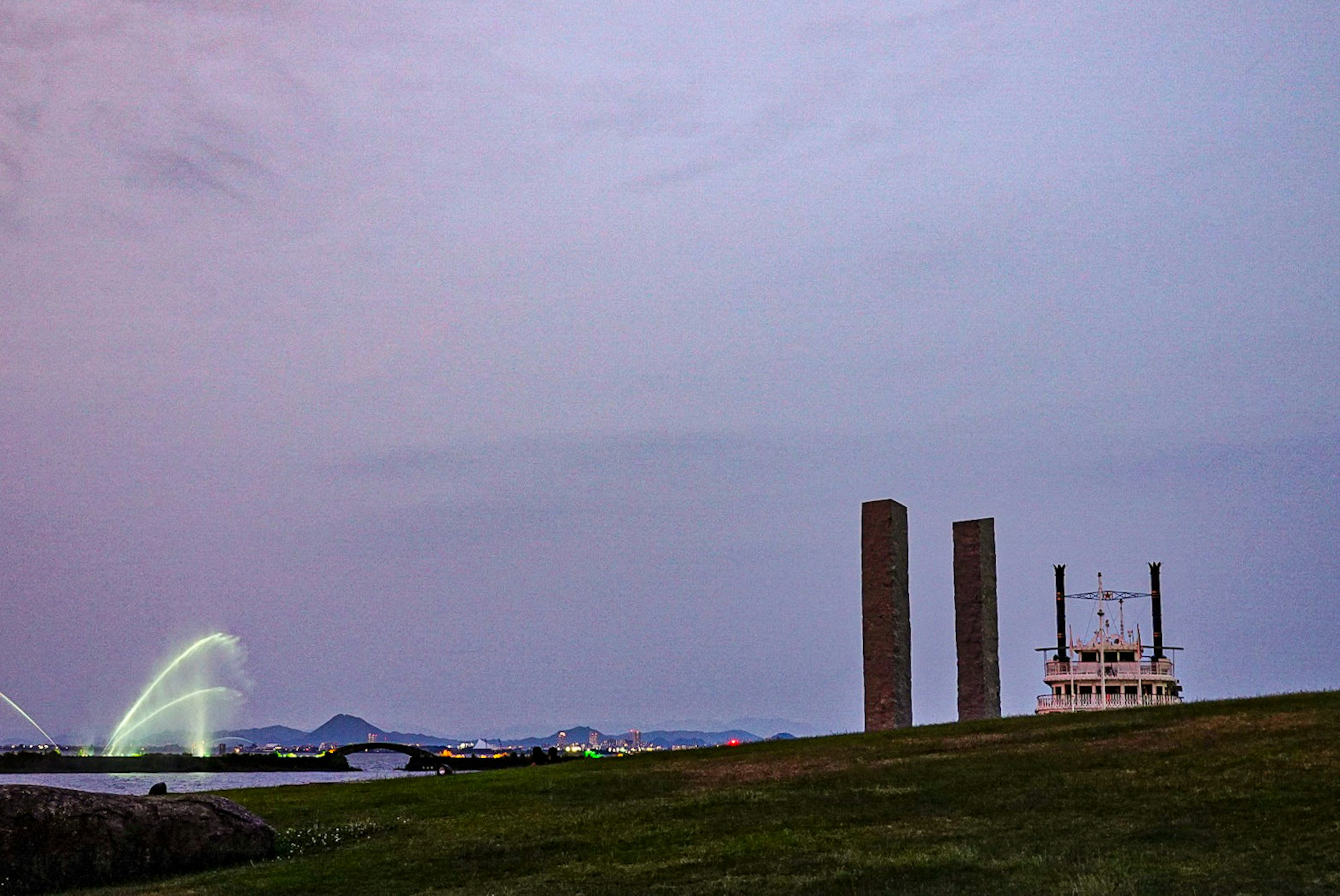 夕暮れ時の川岸にある二本の高い柱と船が見える風景