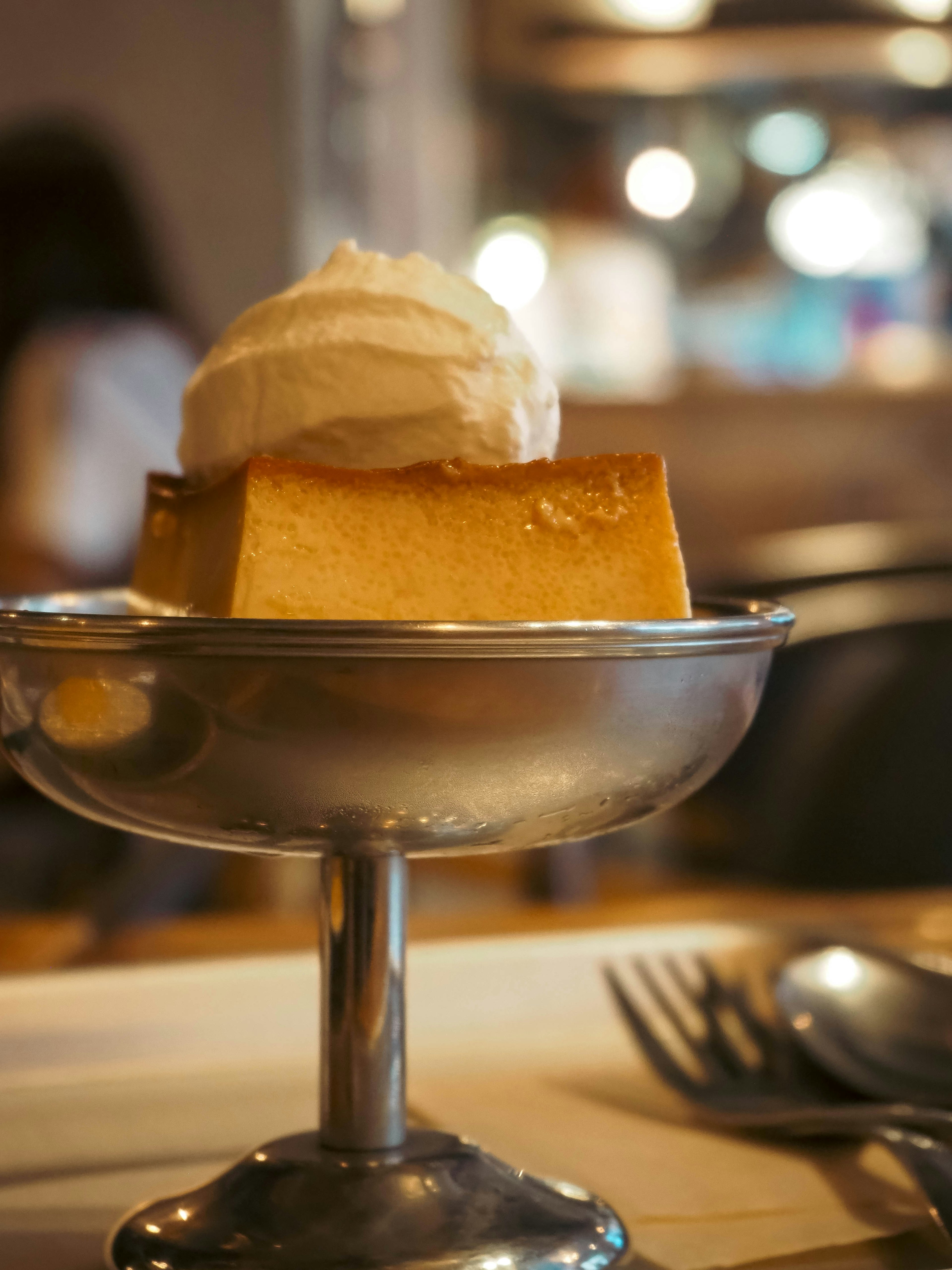 A slice of dessert topped with cream placed in a silver dish