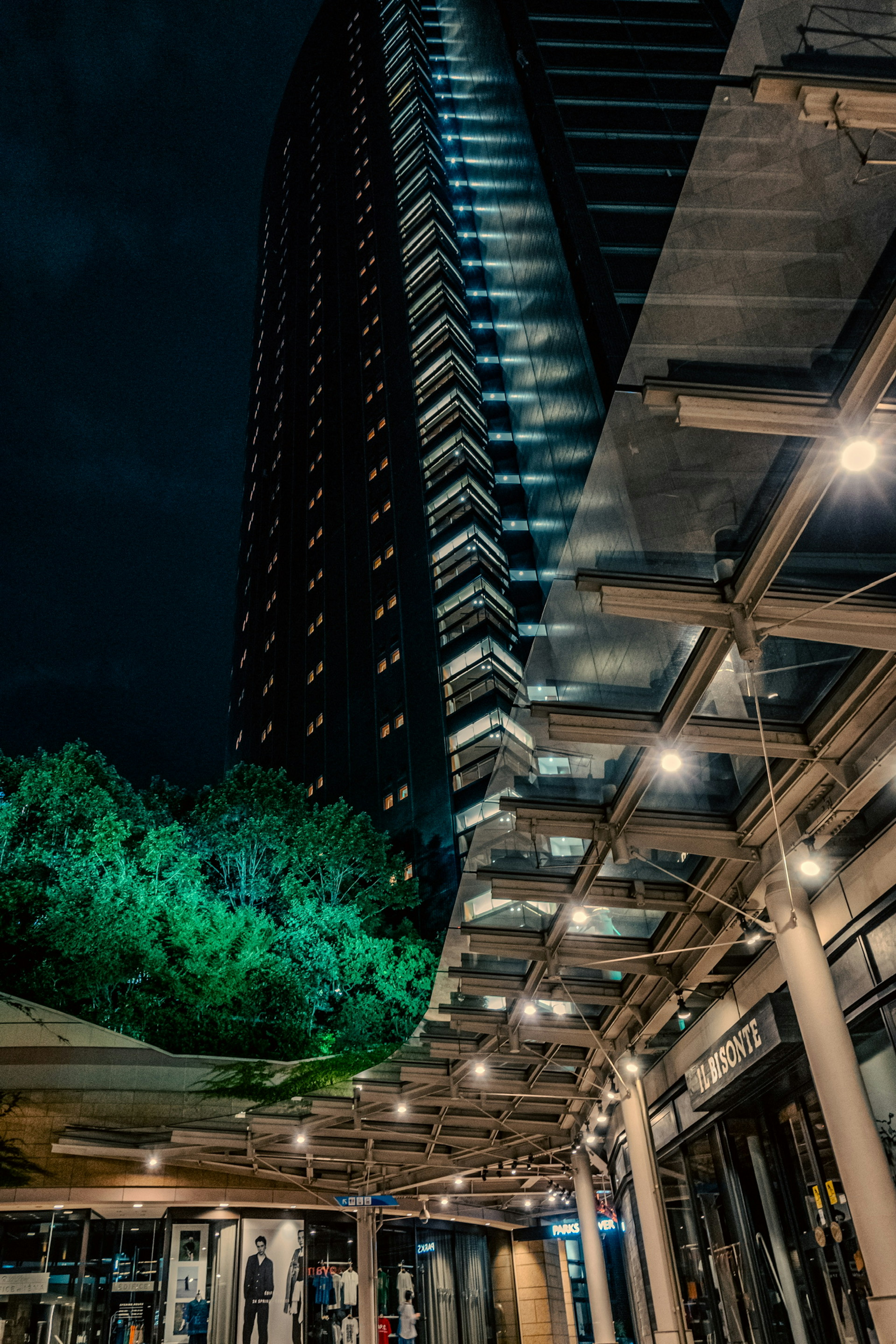 Paesaggio urbano notturno con un grattacielo e alberi verdi in contrasto illuminati splendidamente