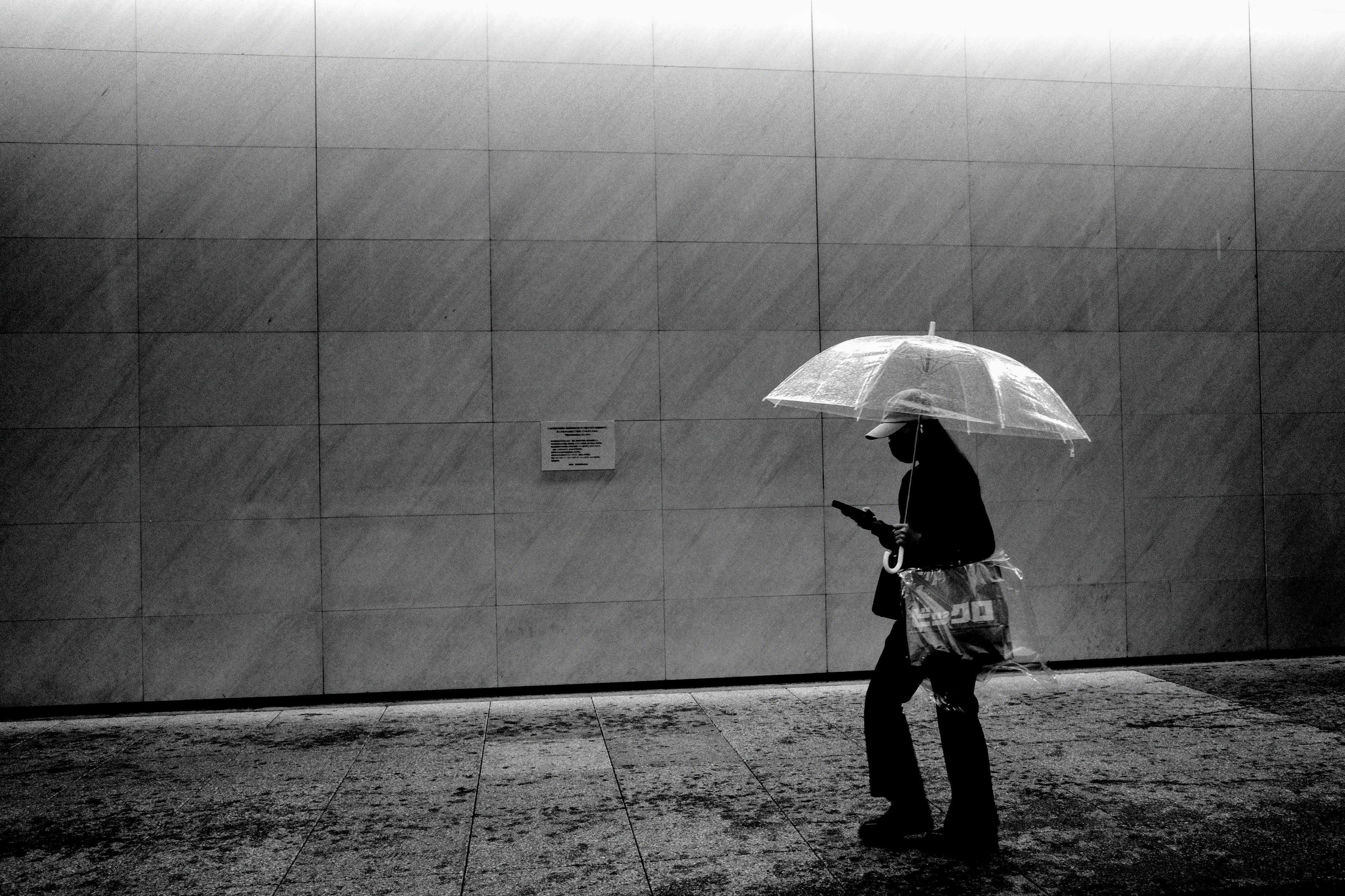 Person, die mit einem weißen Regenschirm in einem monochromen Bild geht