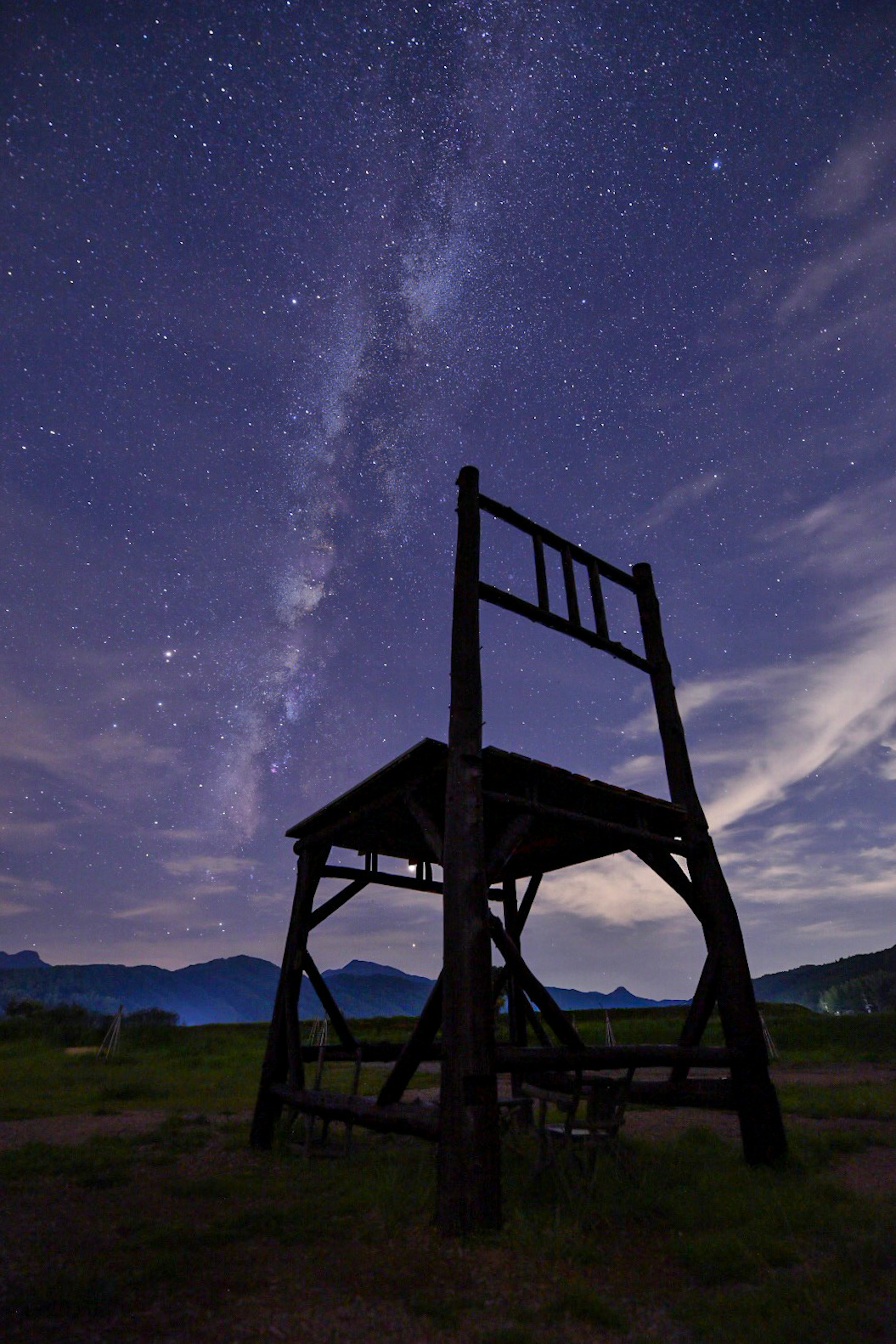 Grande sedia in legno sotto un cielo stellato con la Via Lattea