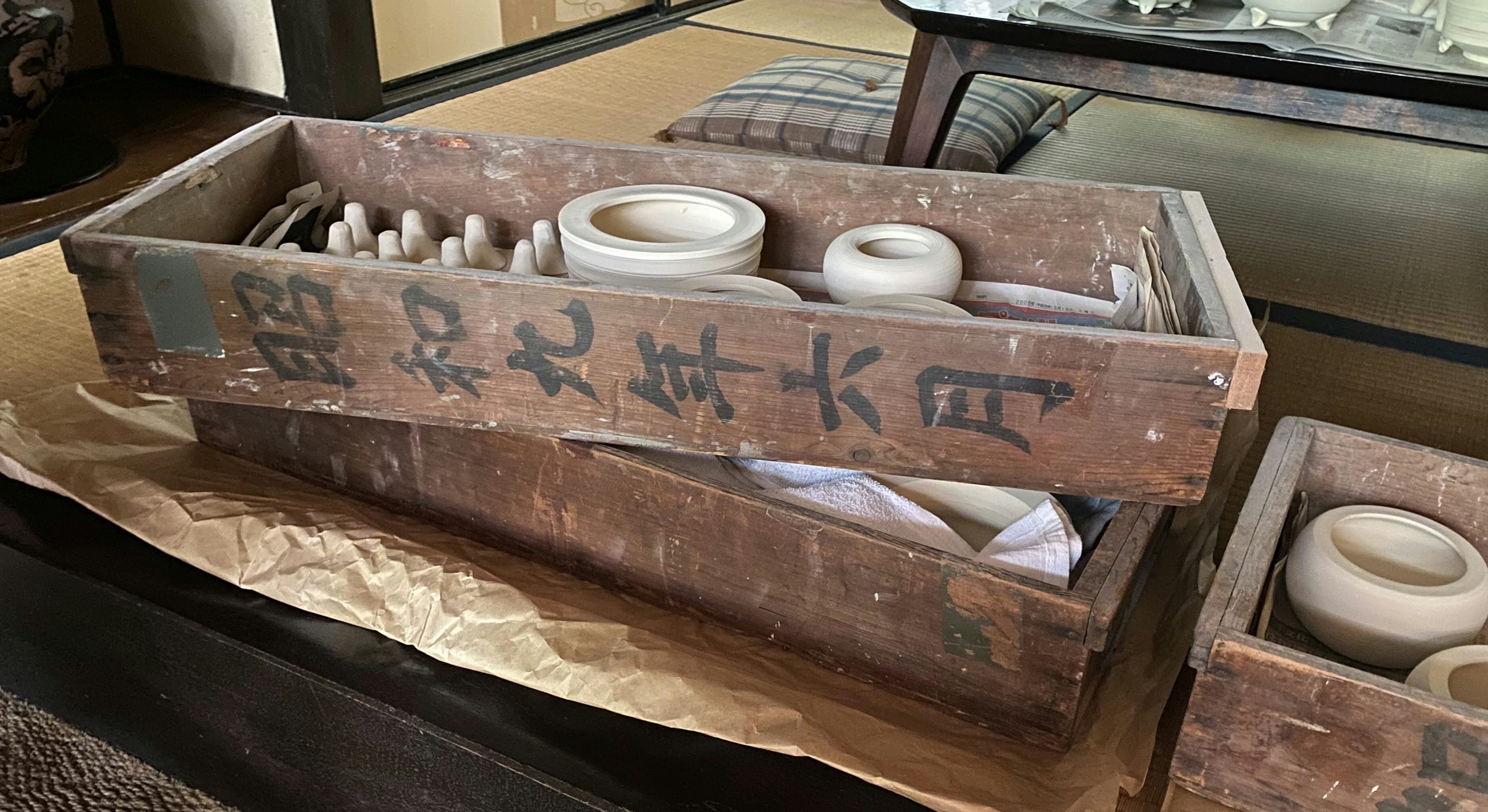 An old wooden box containing ceramic dishes and tools