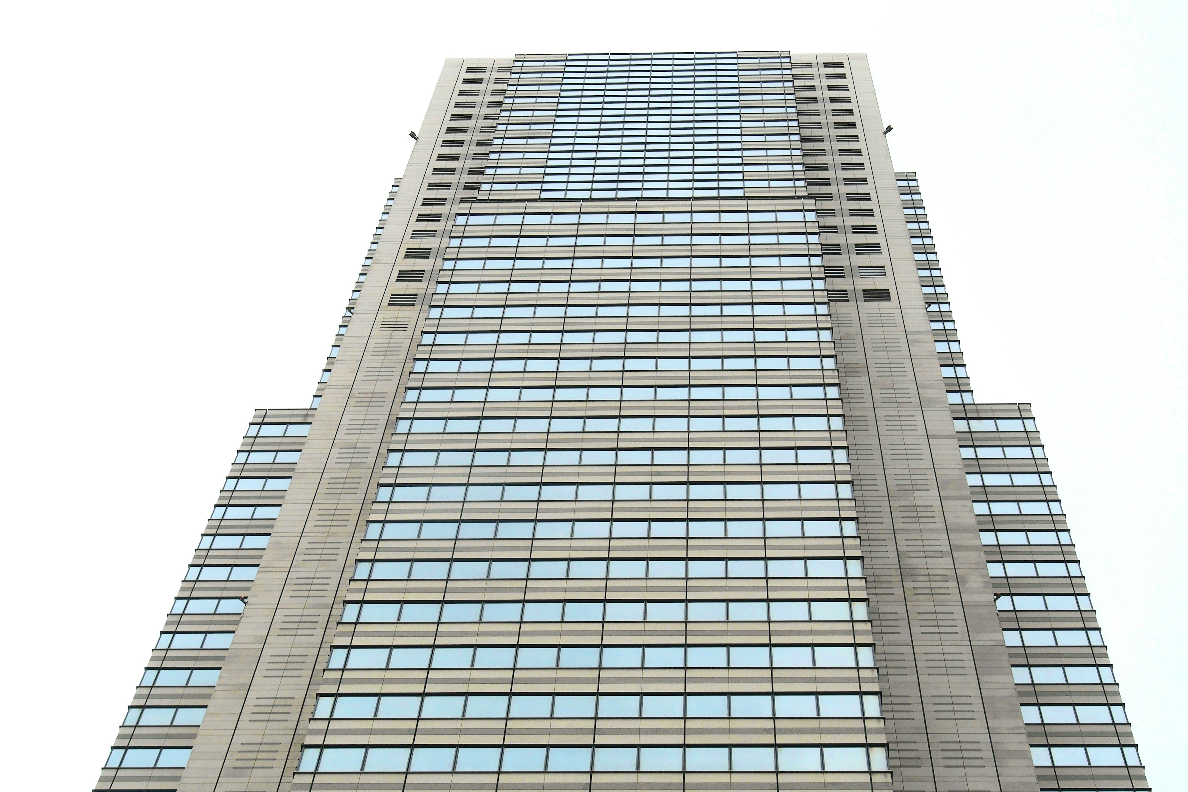 View looking up at a tall building featuring numerous transparent windows