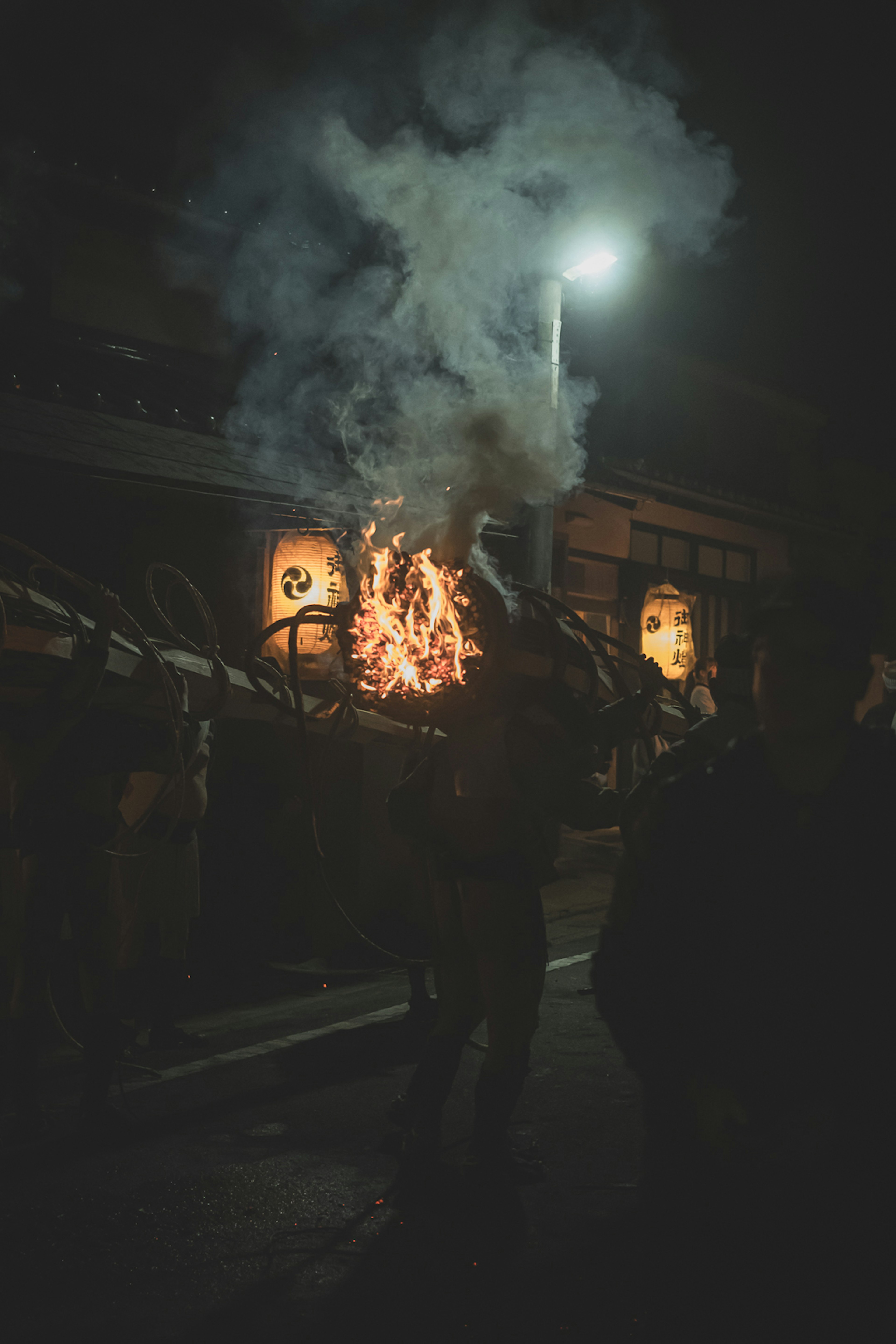 People holding fire in a nighttime festival scene with smoke