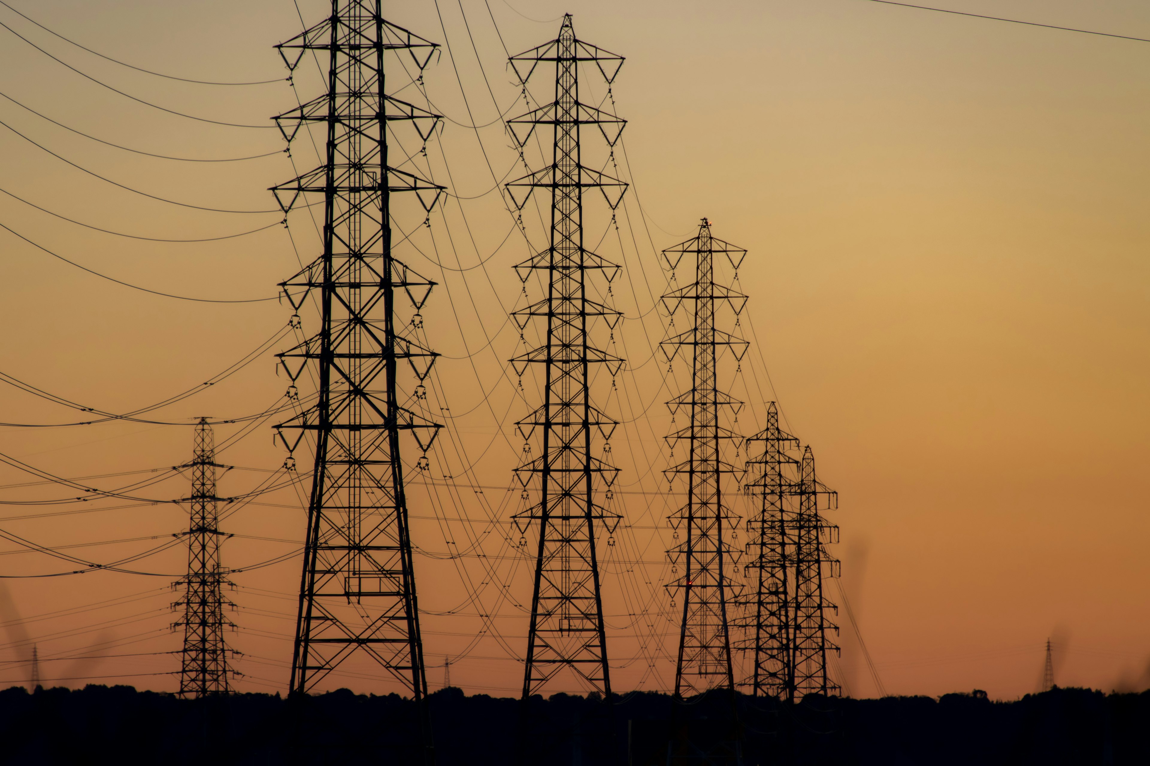 Transmission towers silhouetted against a sunset sky