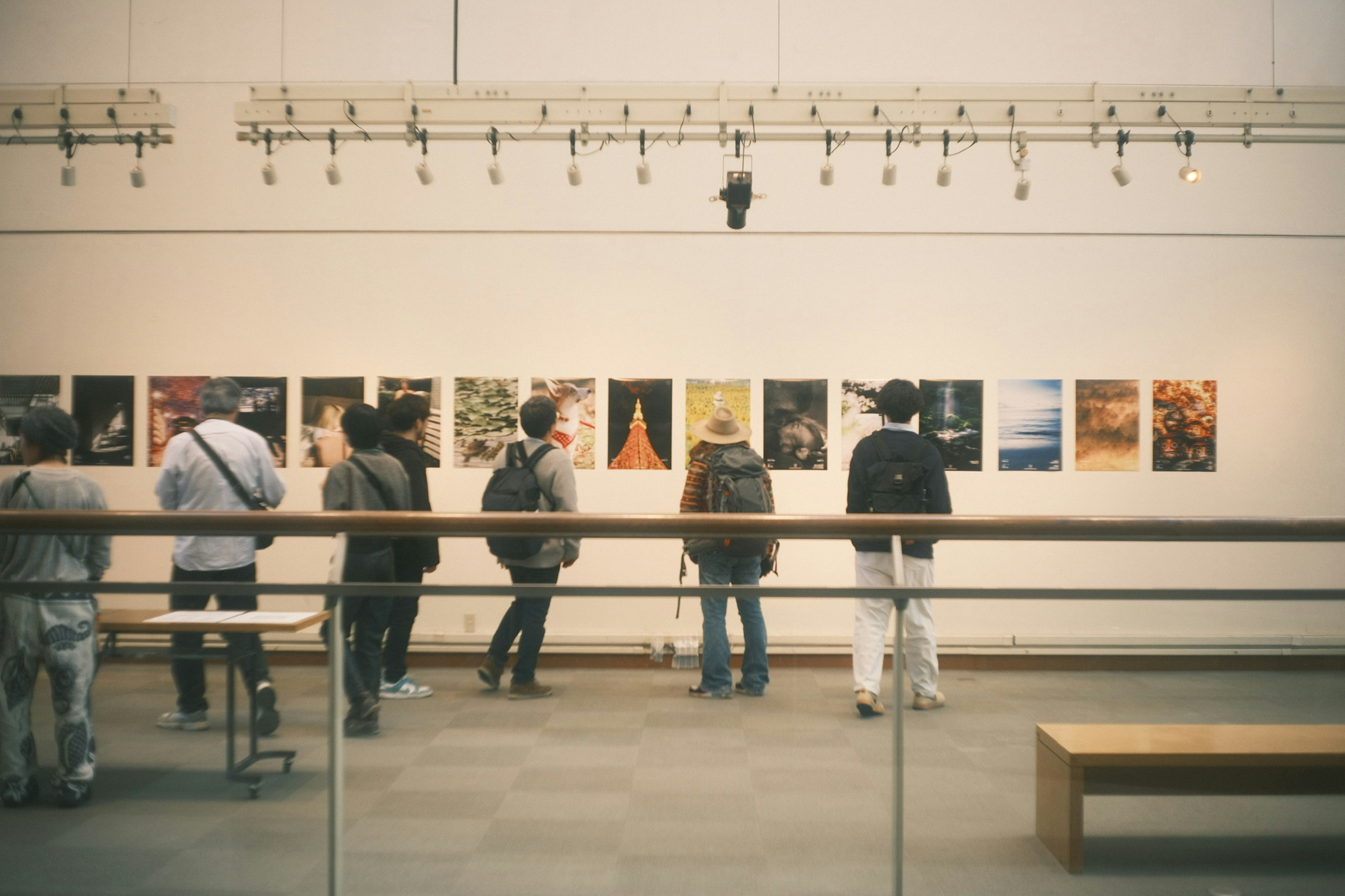 Line of people viewing artwork in a gallery with posters on the wall