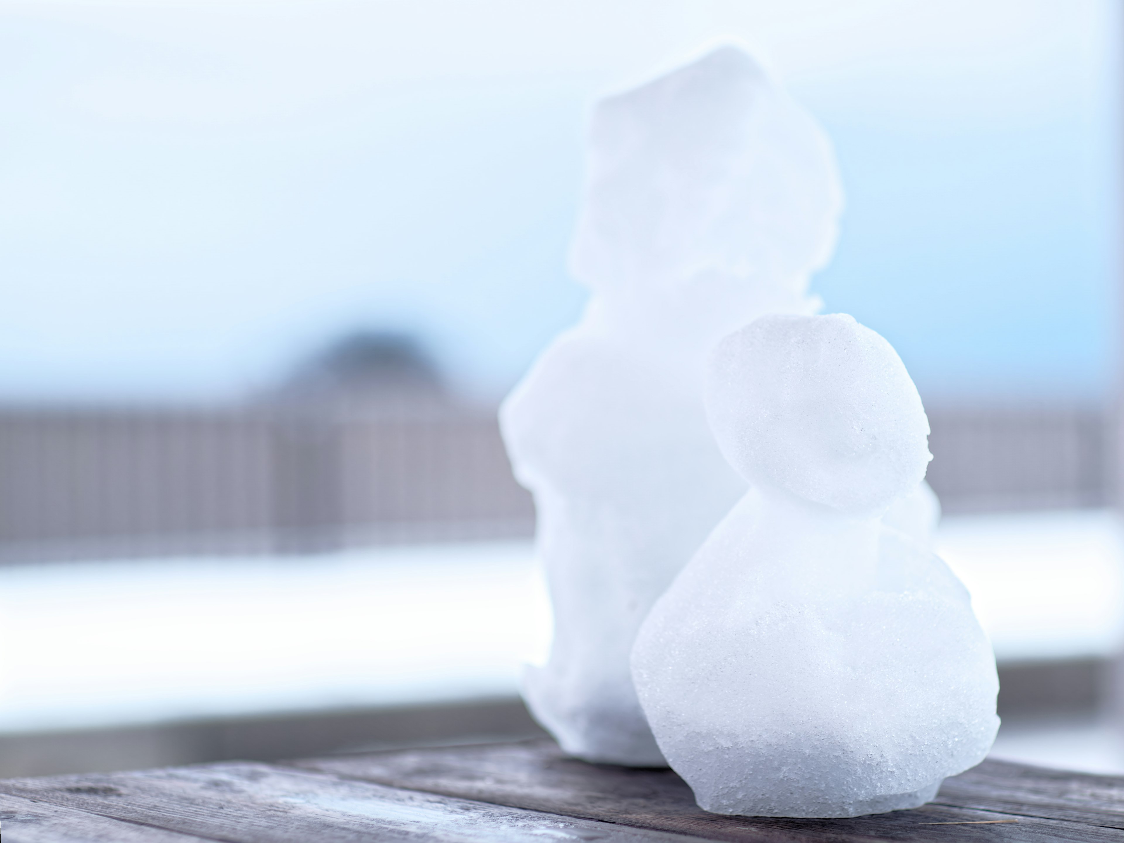 Deux figures en neige placées sur une table en bois