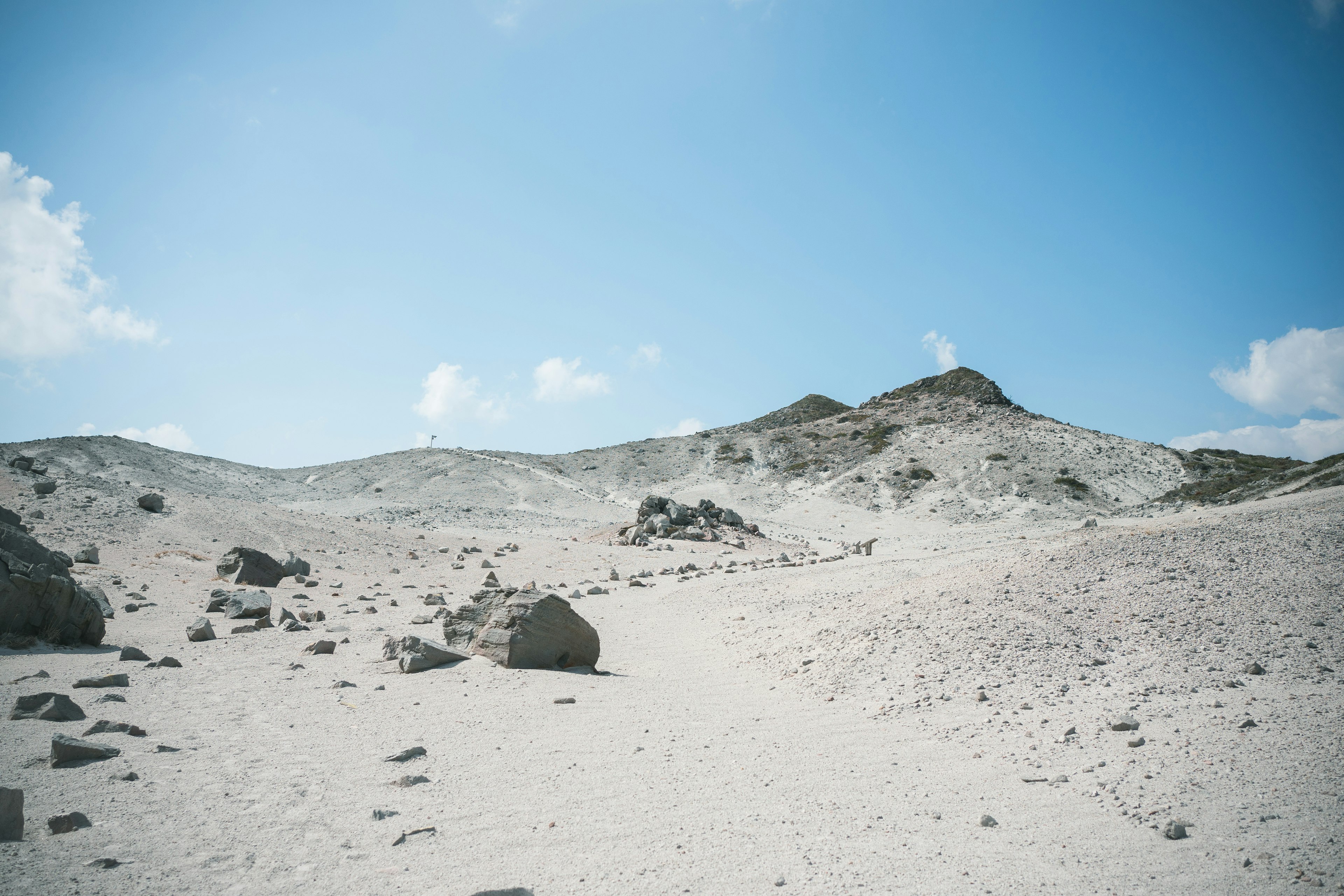 Vaste paysage désertique avec ciel bleu et nuages blancs grandes roches éparpillées