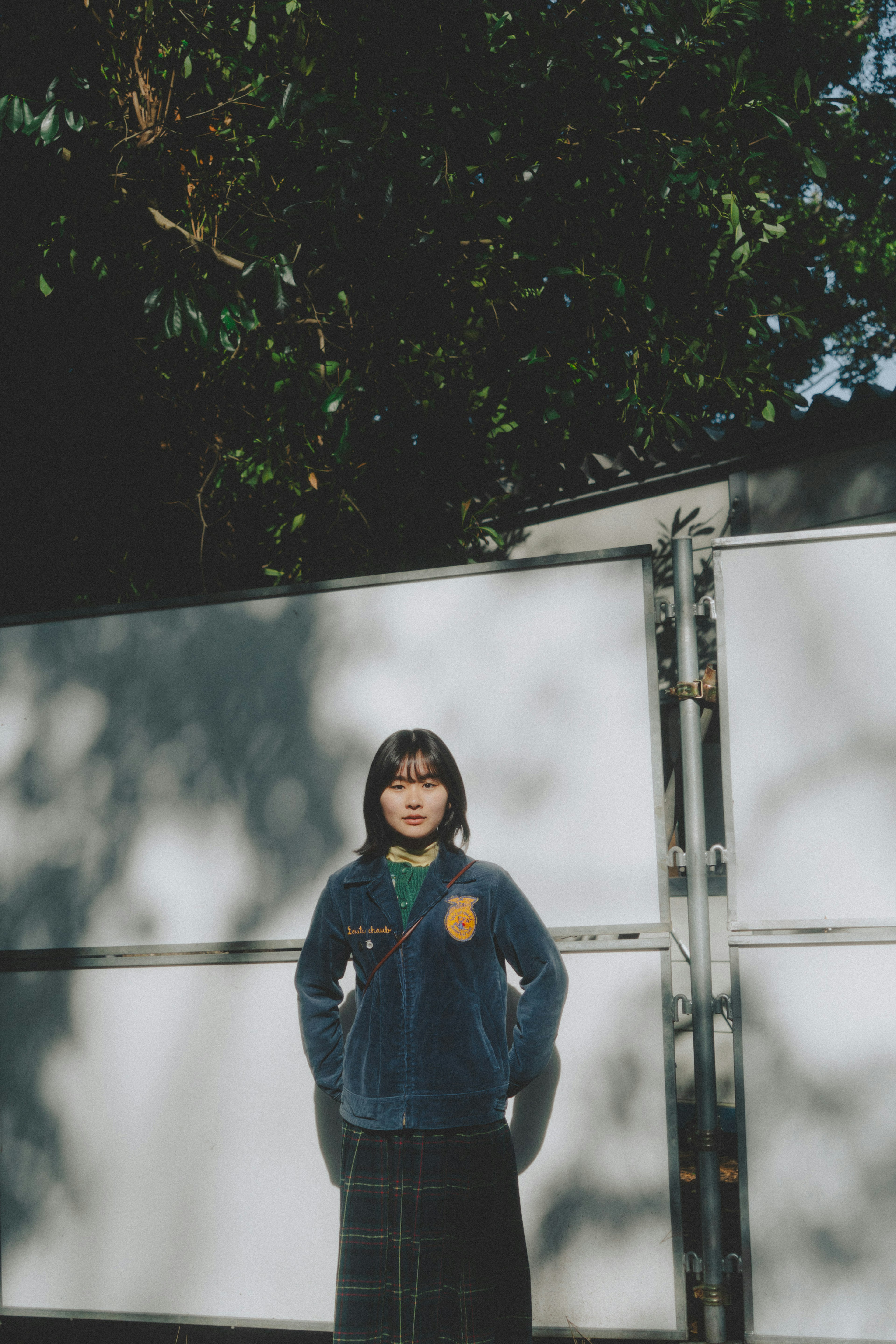 A girl in a blue sweater standing in front of a white fence